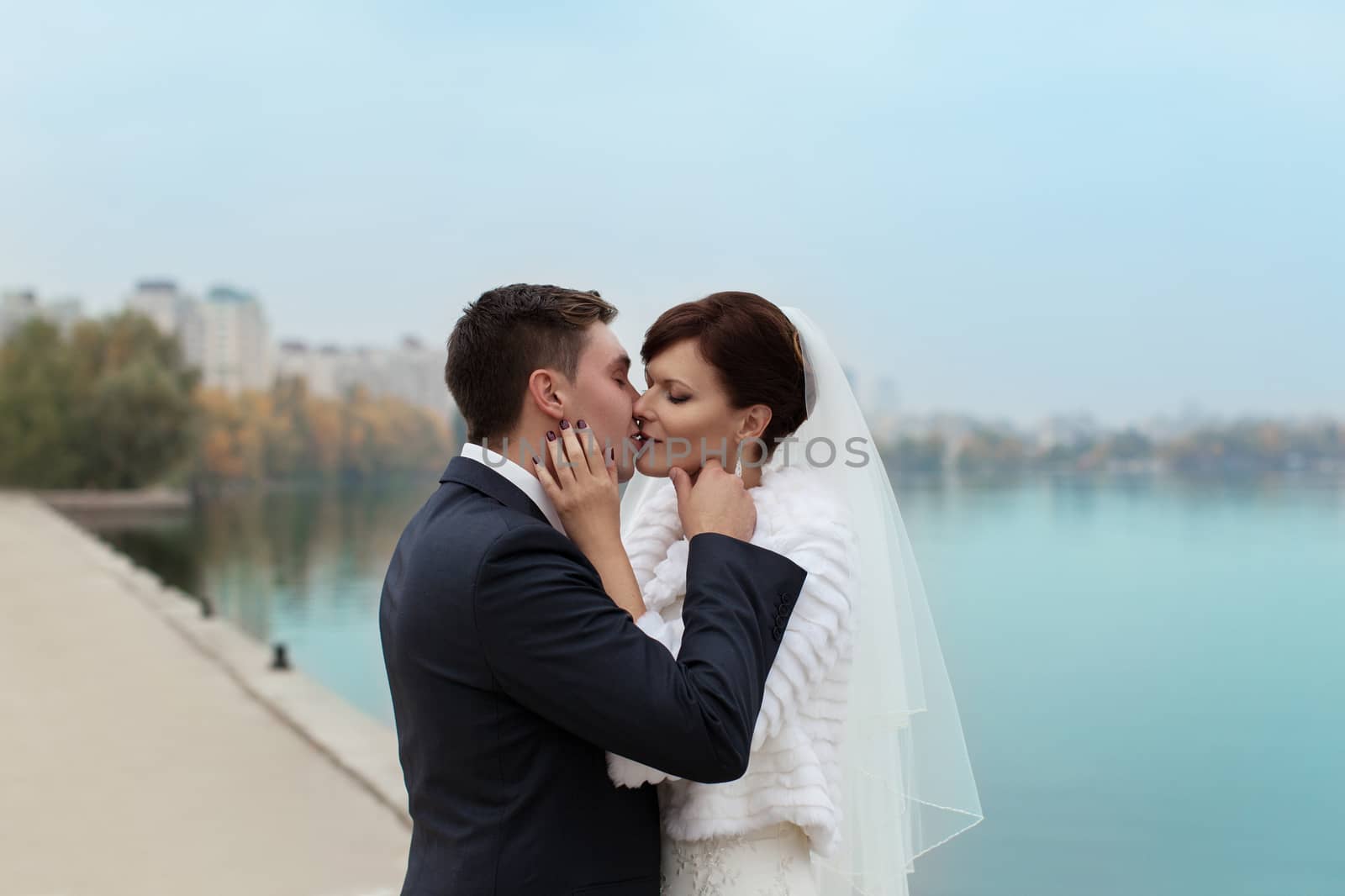 groom gently touched to the bride on a pier near the sea