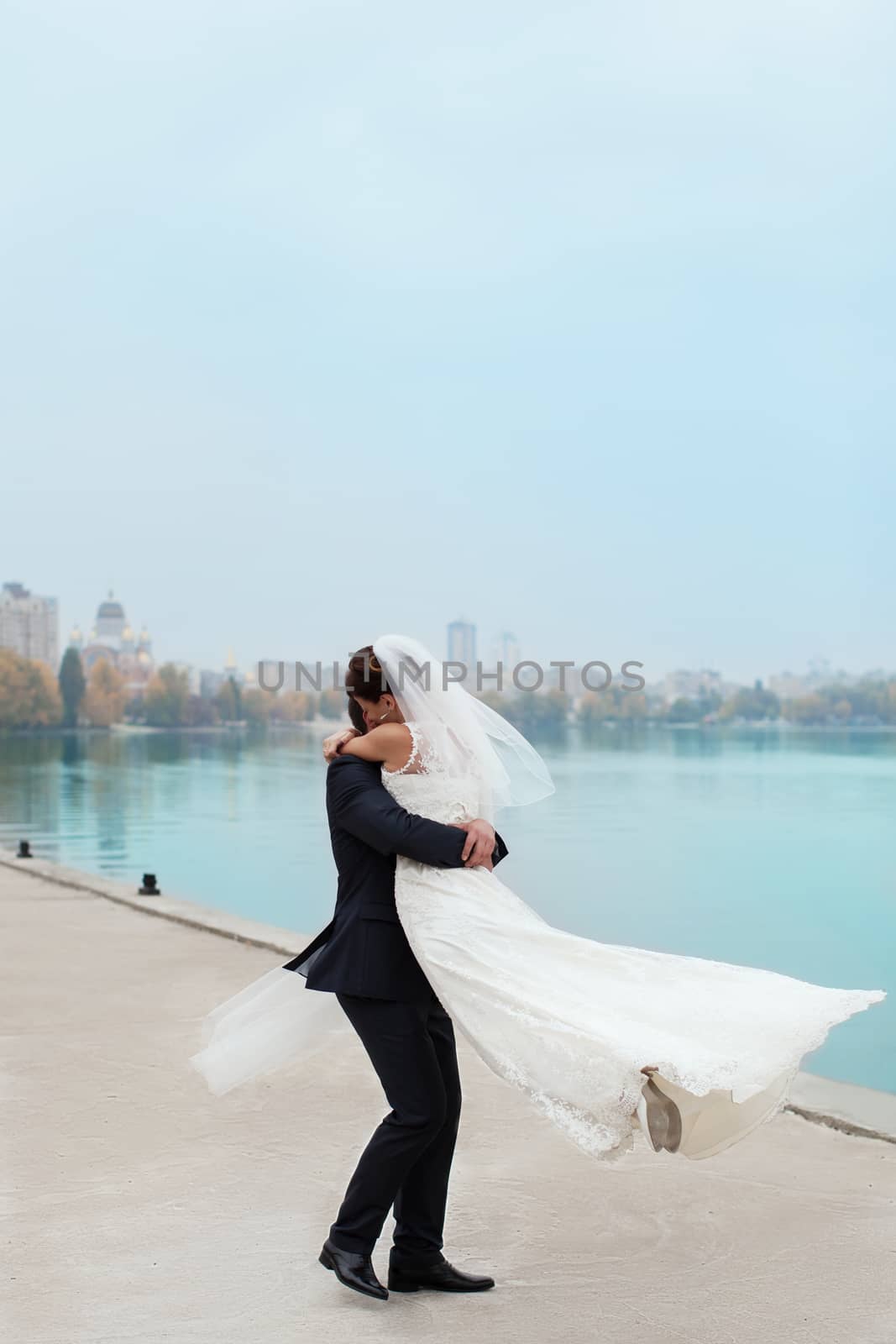 groom gently touched to the bride on a pier near the sea