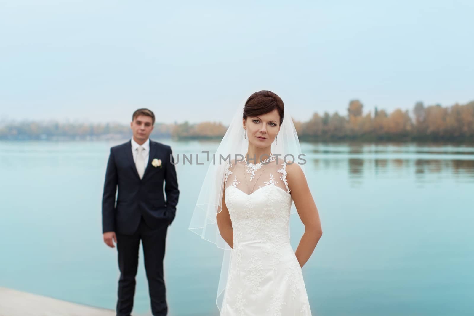 groom gently touched to the bride on a pier near the sea