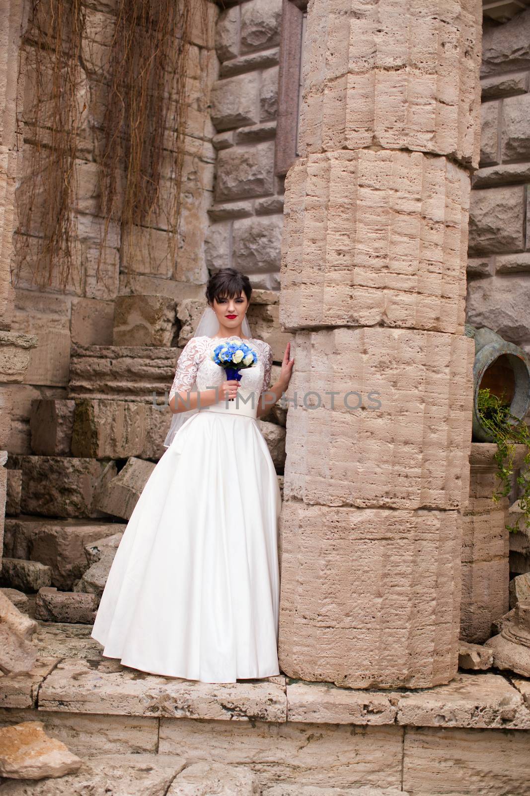 Bride holding bouquet, smiling at the camera on a rainy day