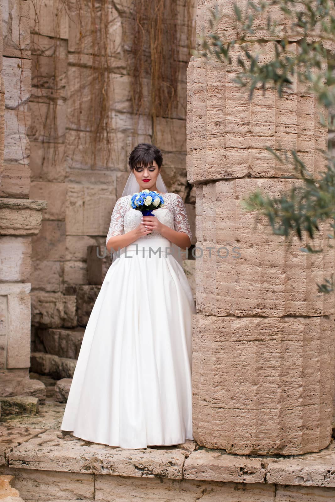 Bride holding bouquet, smiling at the camera on a rainy day