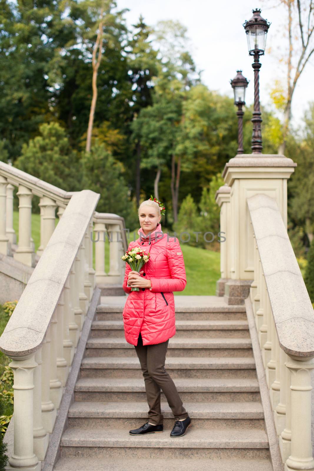 The blonde in a red jacket with a bouquet of flowers