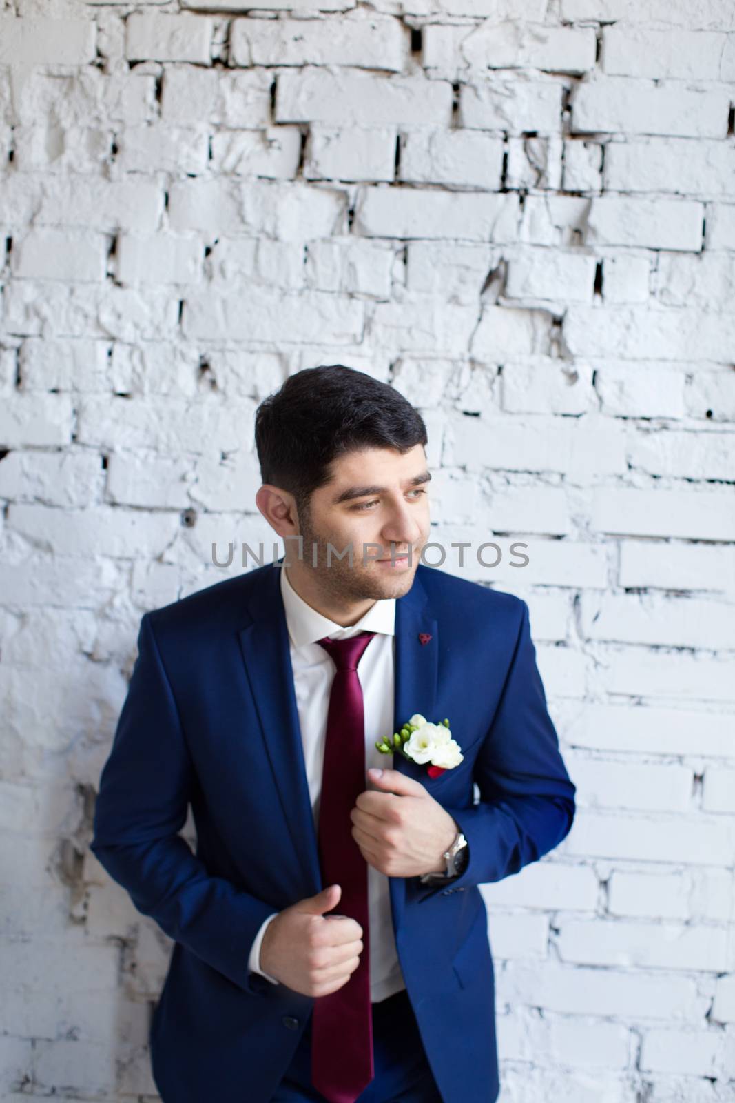 gorgeous brunette bride putting on boutonniere on the blue suit of groom