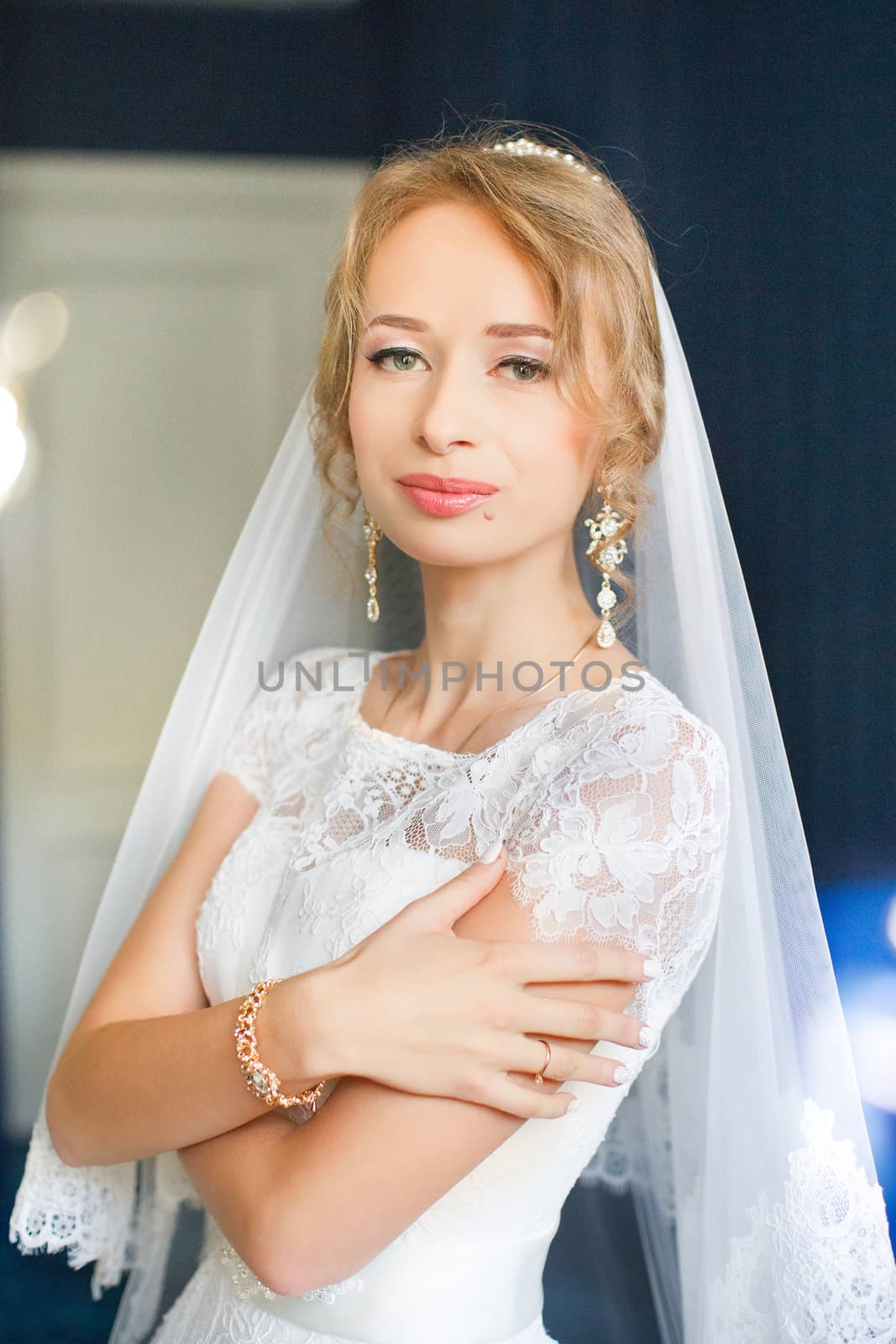 Portrait of beautiful bride with fashion veil posing on bed at wedding morning. Makeup. Brunette girl with long wavy hair styling. Wedding dress. by lanser314