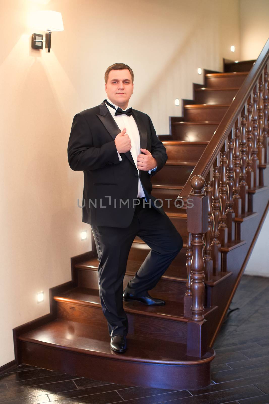 A close-up shot of a man straightening his tux.