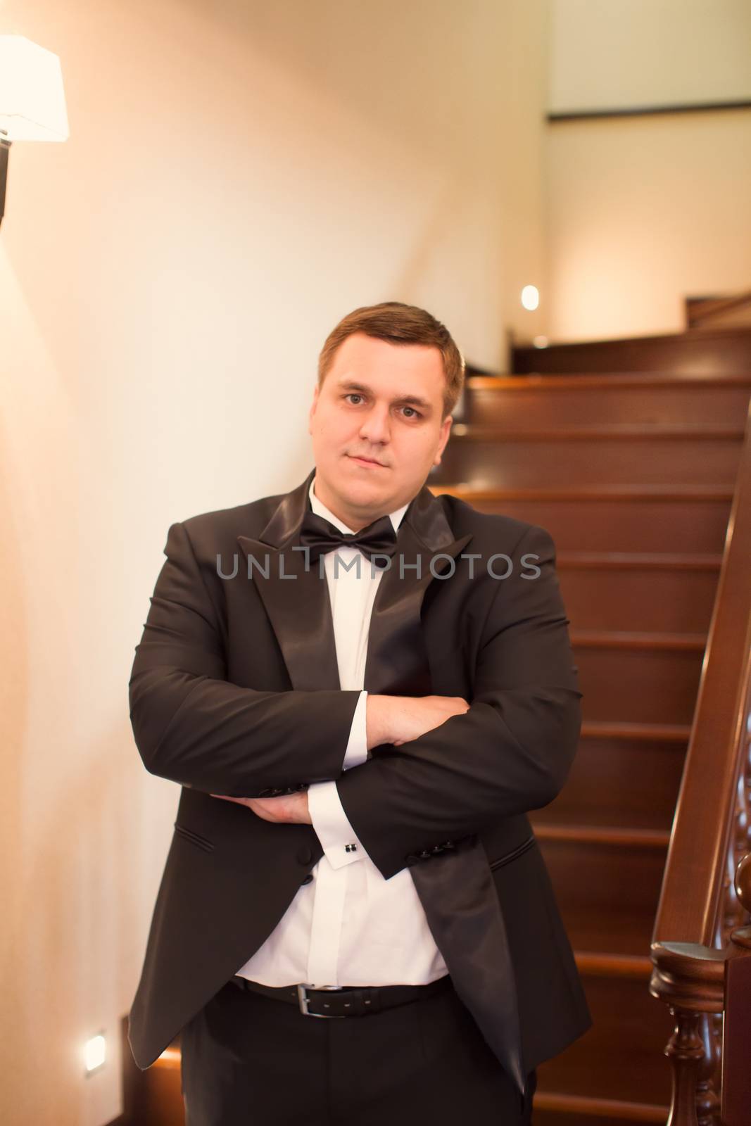 A close-up shot of a man straightening his tux.