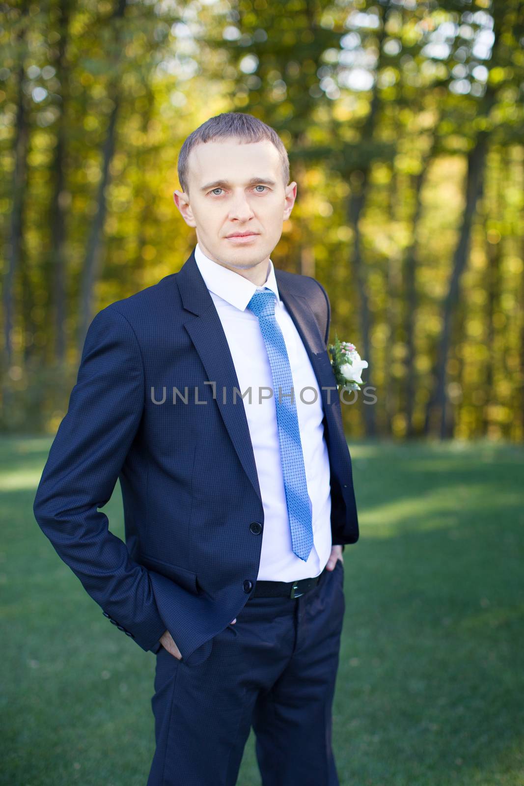 elegant young fashion man in tuxedo holding his hand on his jacket and looking to his side, away from the camera.on black background