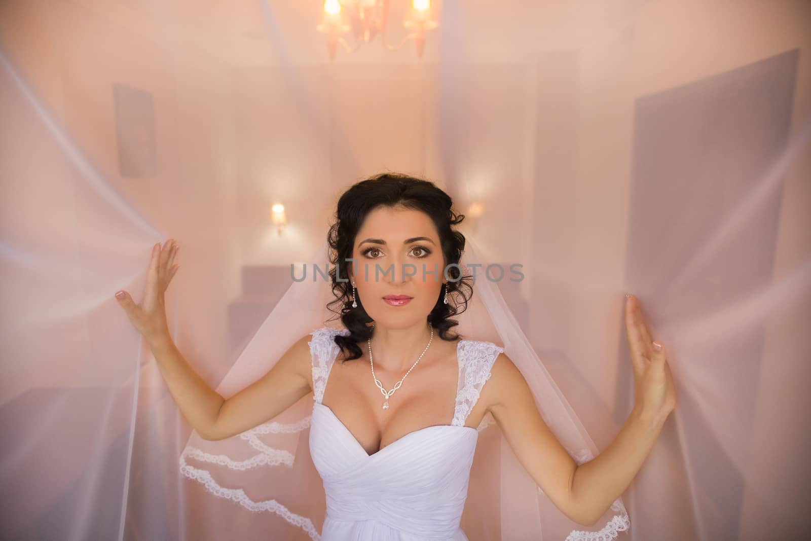 Stylish brunette bride near old vintage pink house with columns