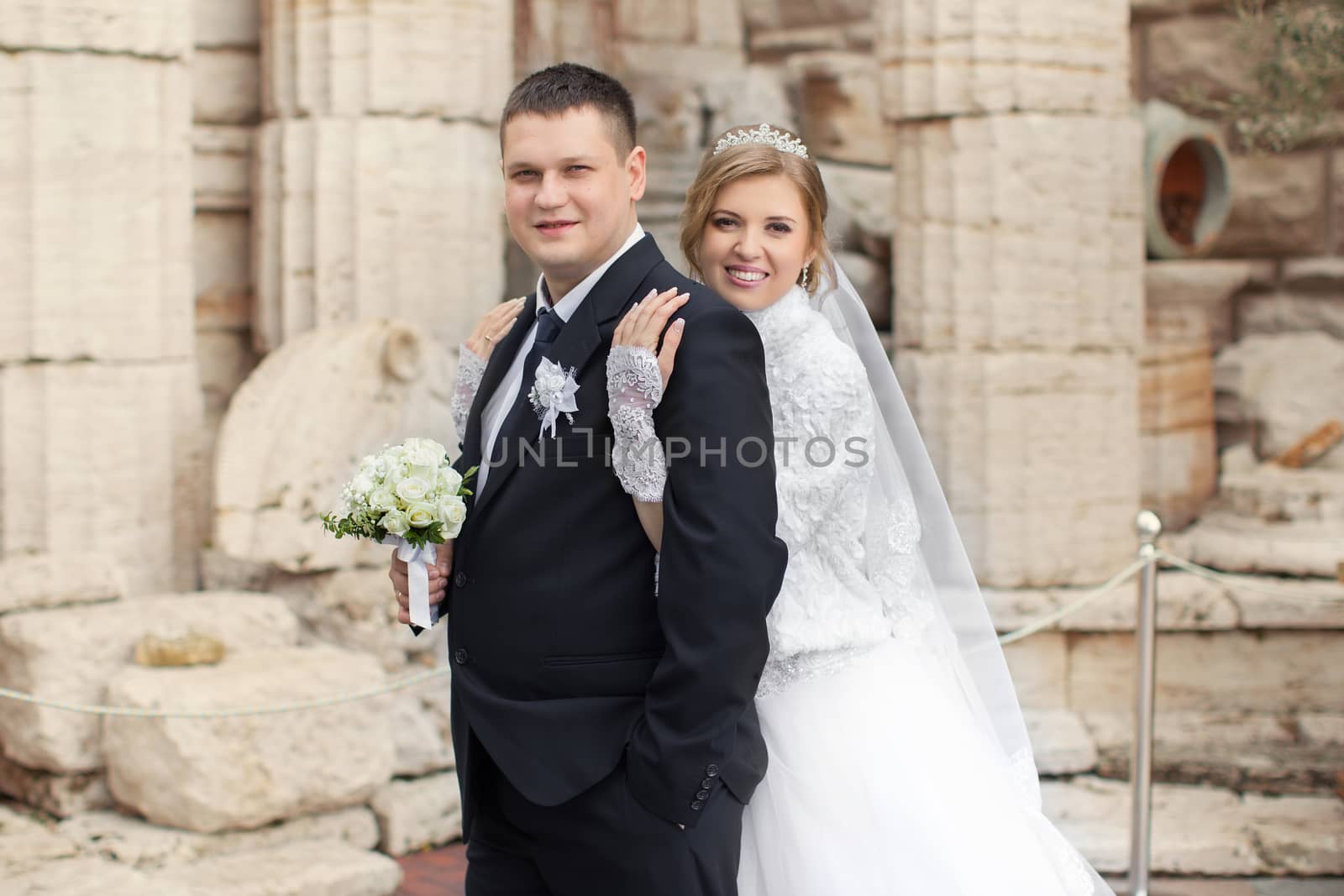 The bride to the groom leaned against the backdrop of a stone wall