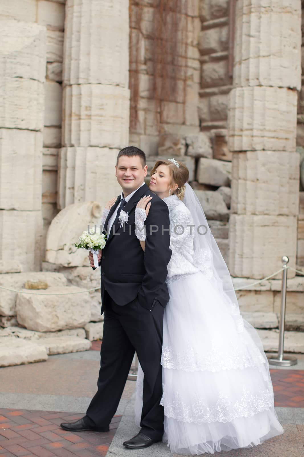 The bride to the groom leaned against the backdrop of a stone wall