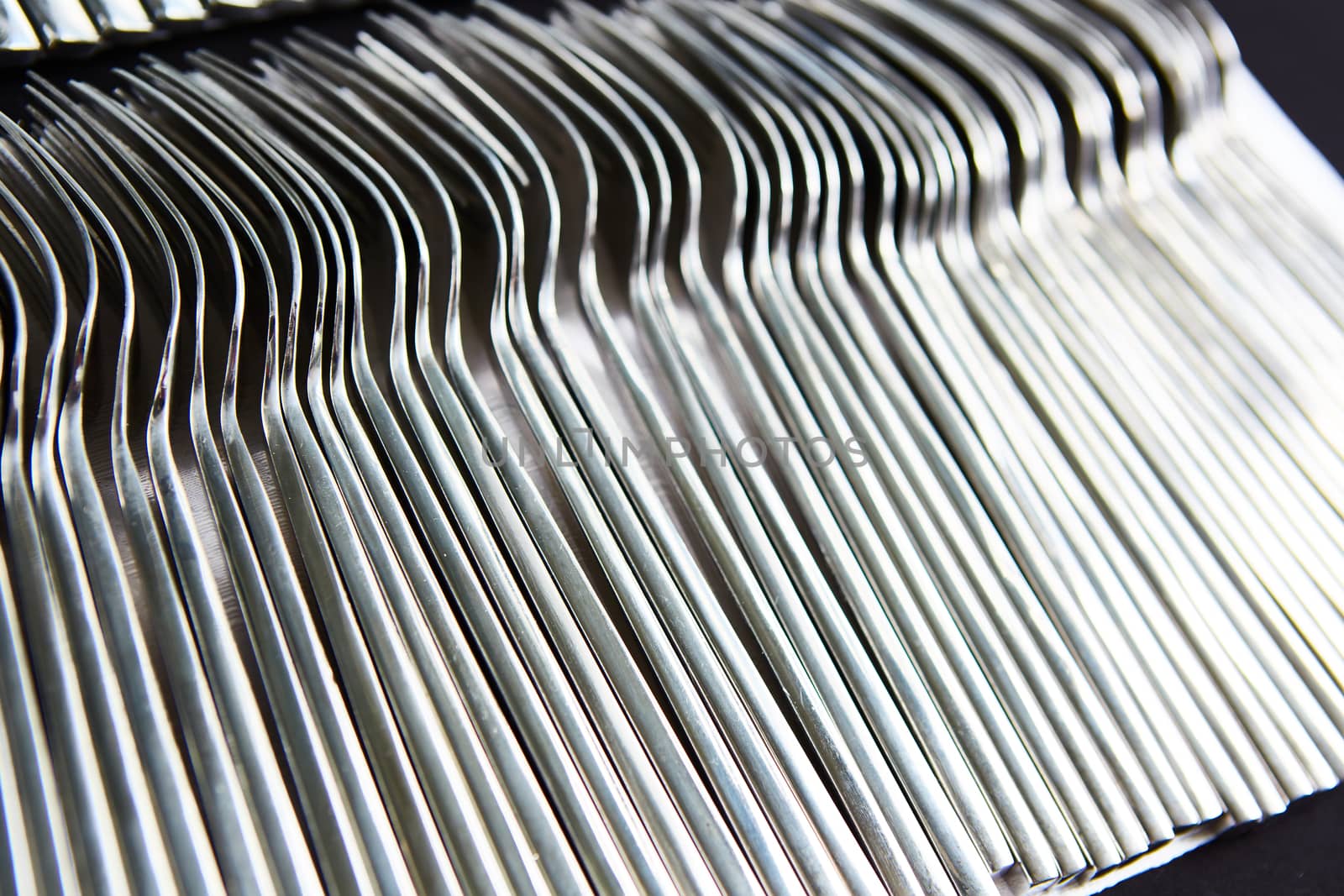 close up of a pile of fork on a tray prepare for event or party. selective focus in warm light room of restaurant