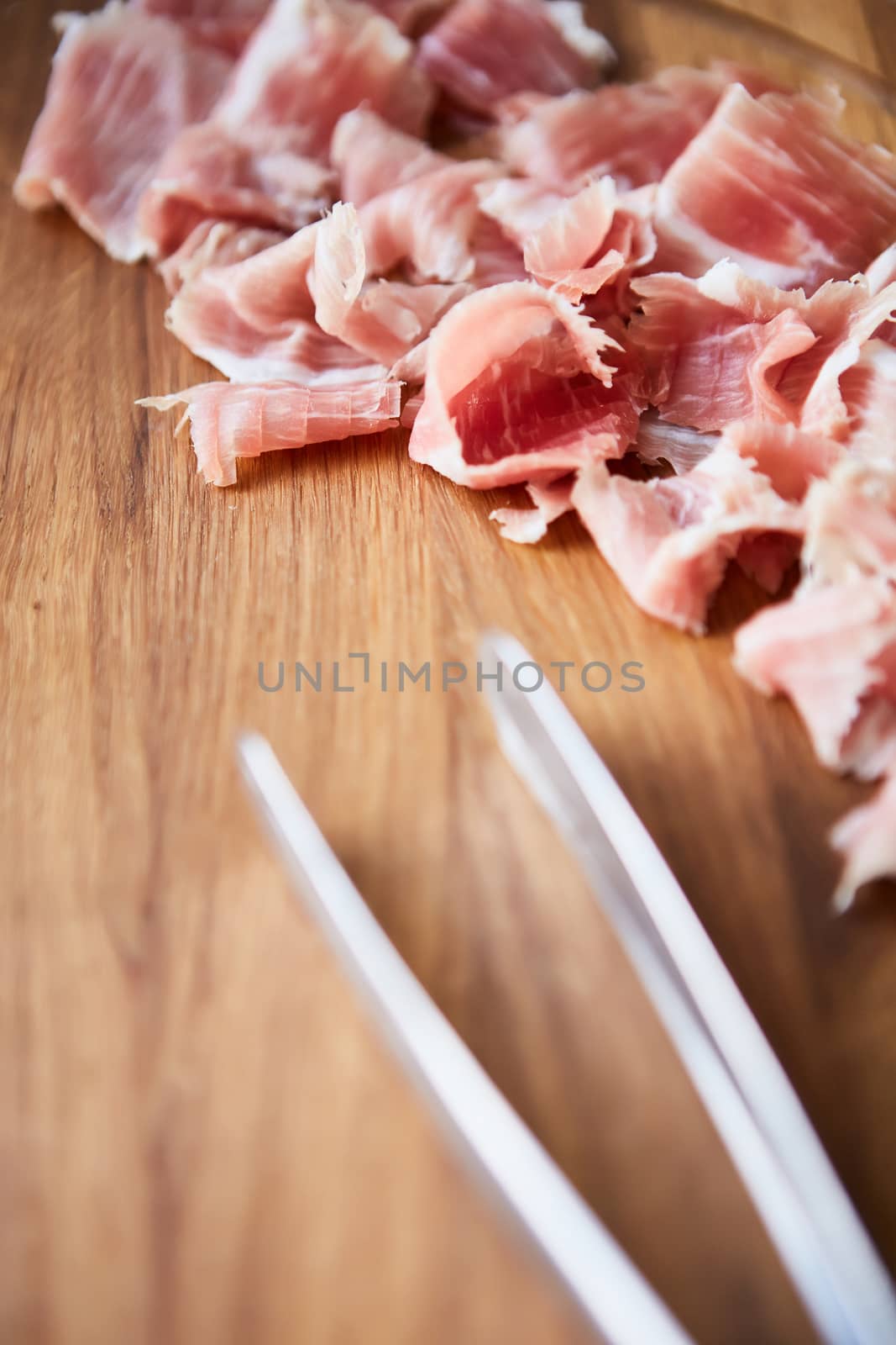 sliced prosciutto on a wooden board by sarymsakov