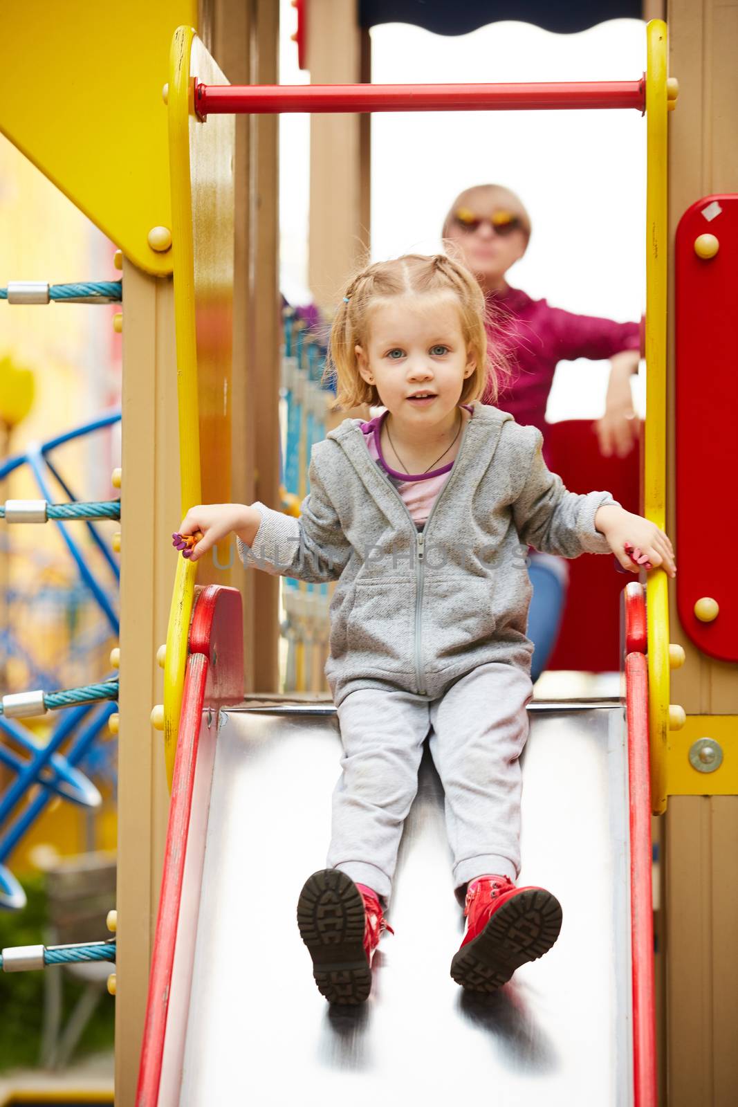 Mother and daughter playing on the playground outdoors by sarymsakov