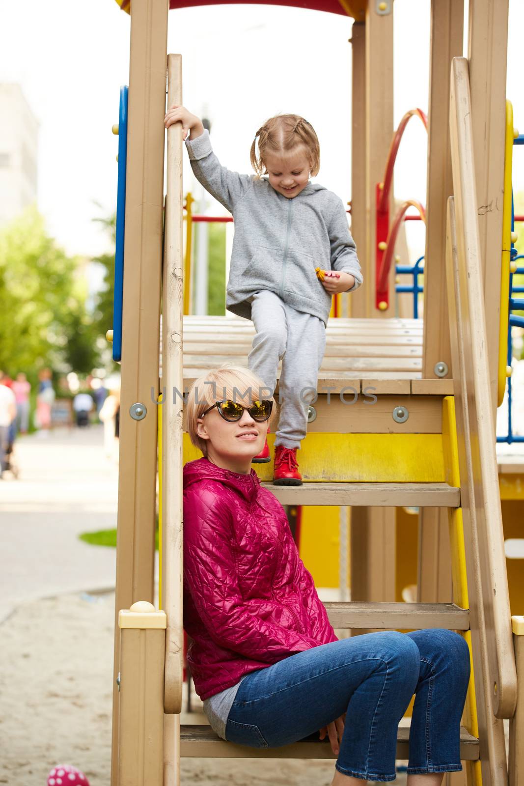 Mother and daughter playing on the playground outdoors by sarymsakov