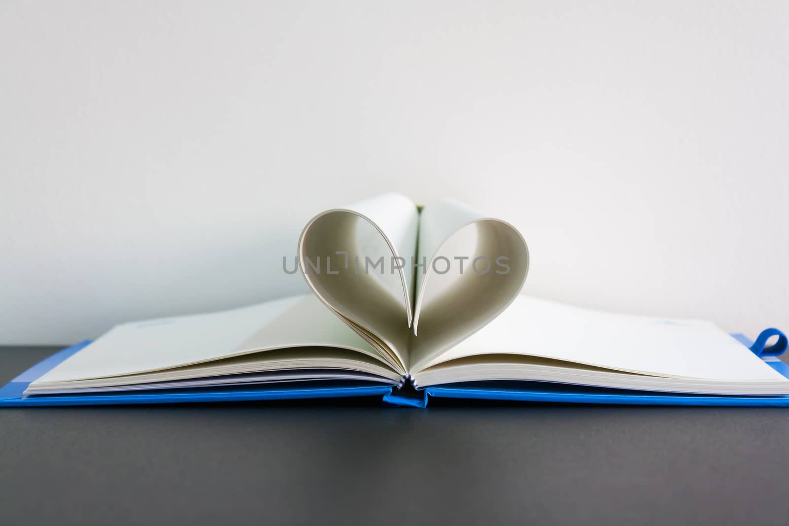 Pages of a book curved into a heart shape on table