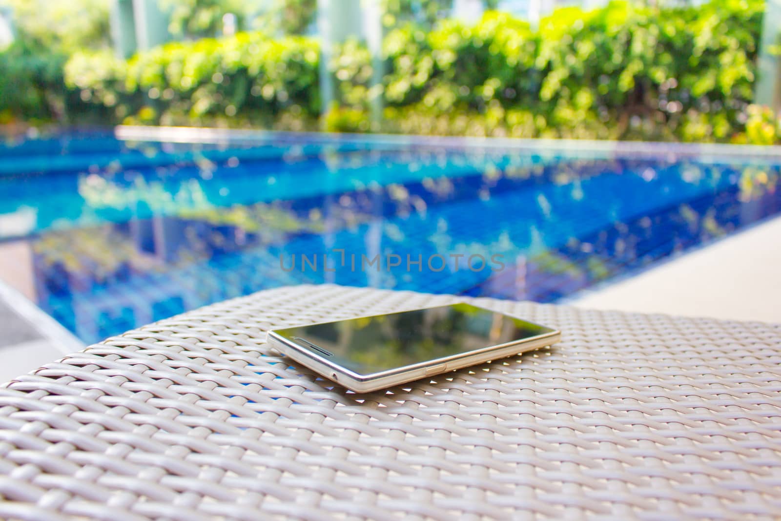 Smartphone put on armchair beside the pool means to get resting  away from business