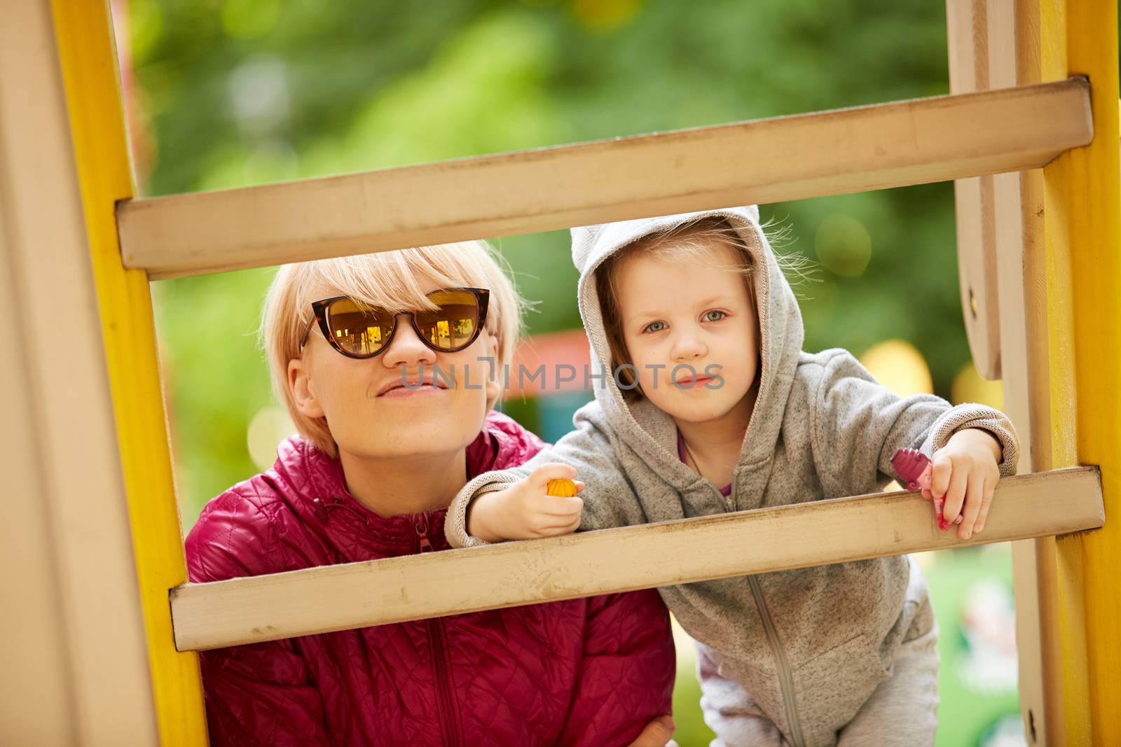 Mother and daughter playing on the playground outdoors by sarymsakov