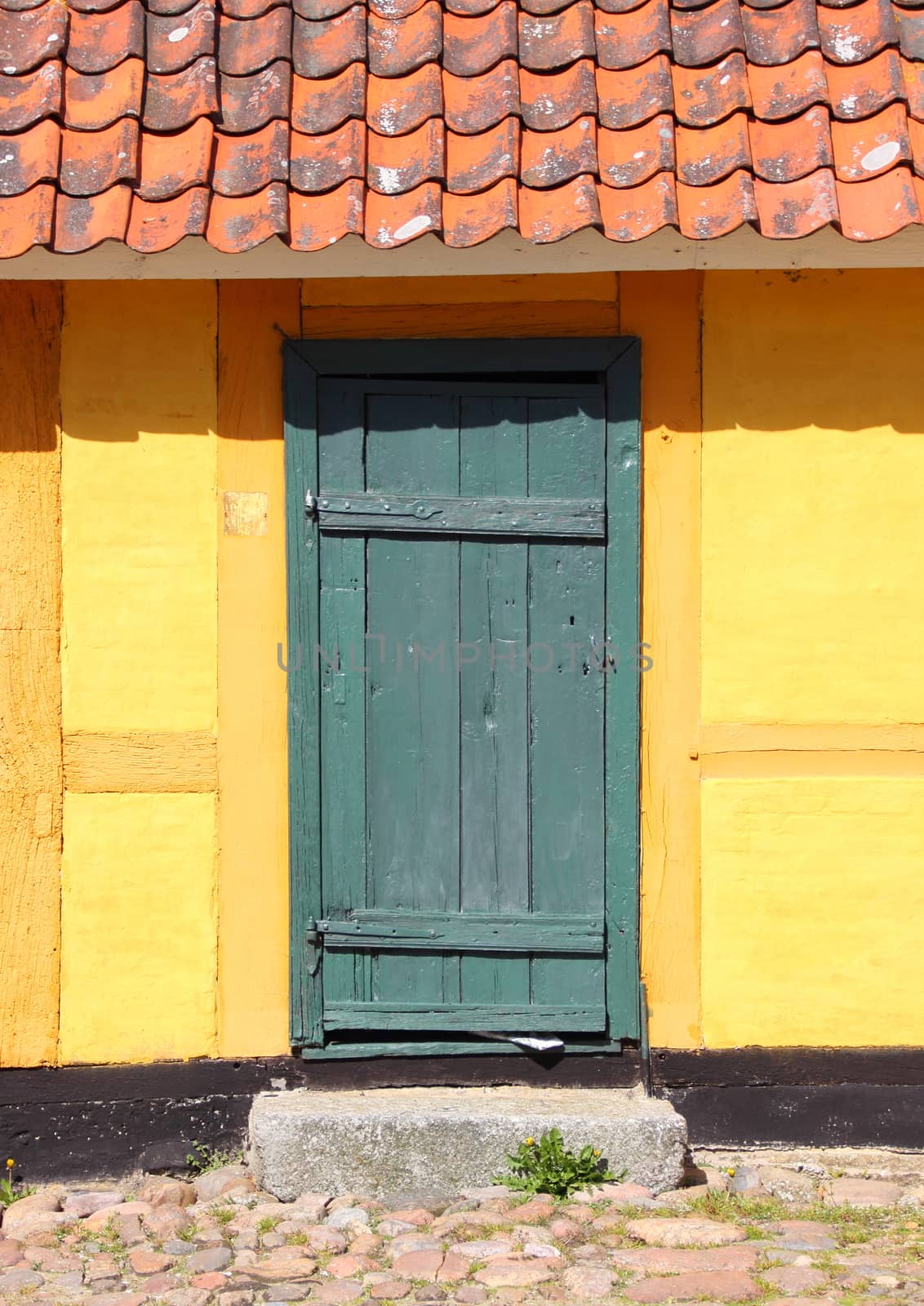 Old wooden door with red tiles and yellow wall