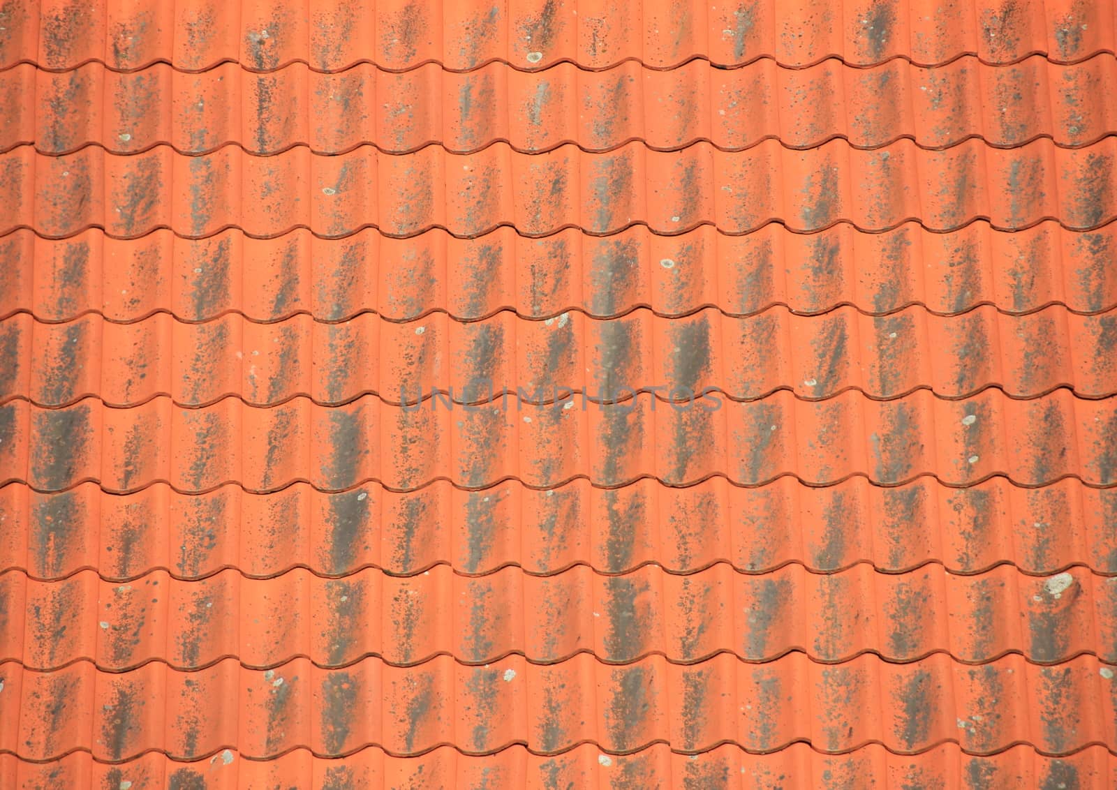 Old red roof tiles with black patina