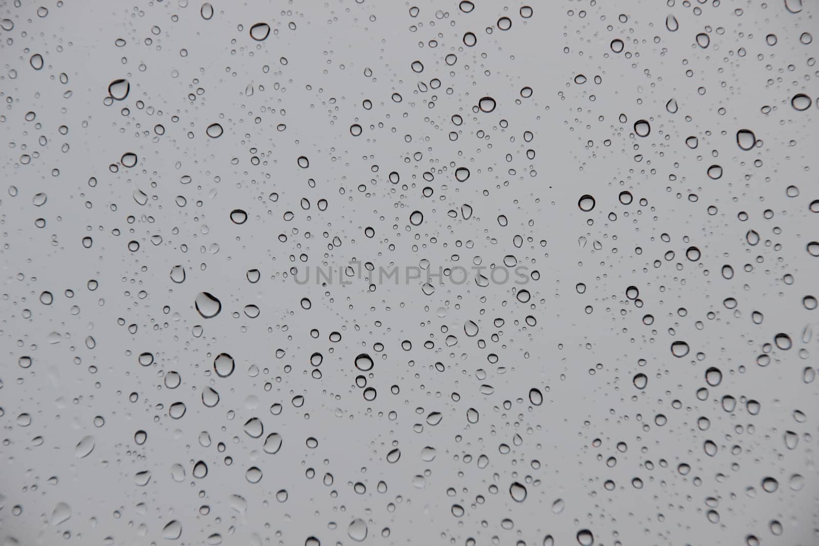 Raindrops on window with black stormy weather outside