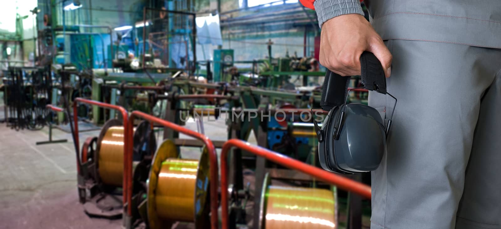 Worker with protective headphone at man hands at industrial factory