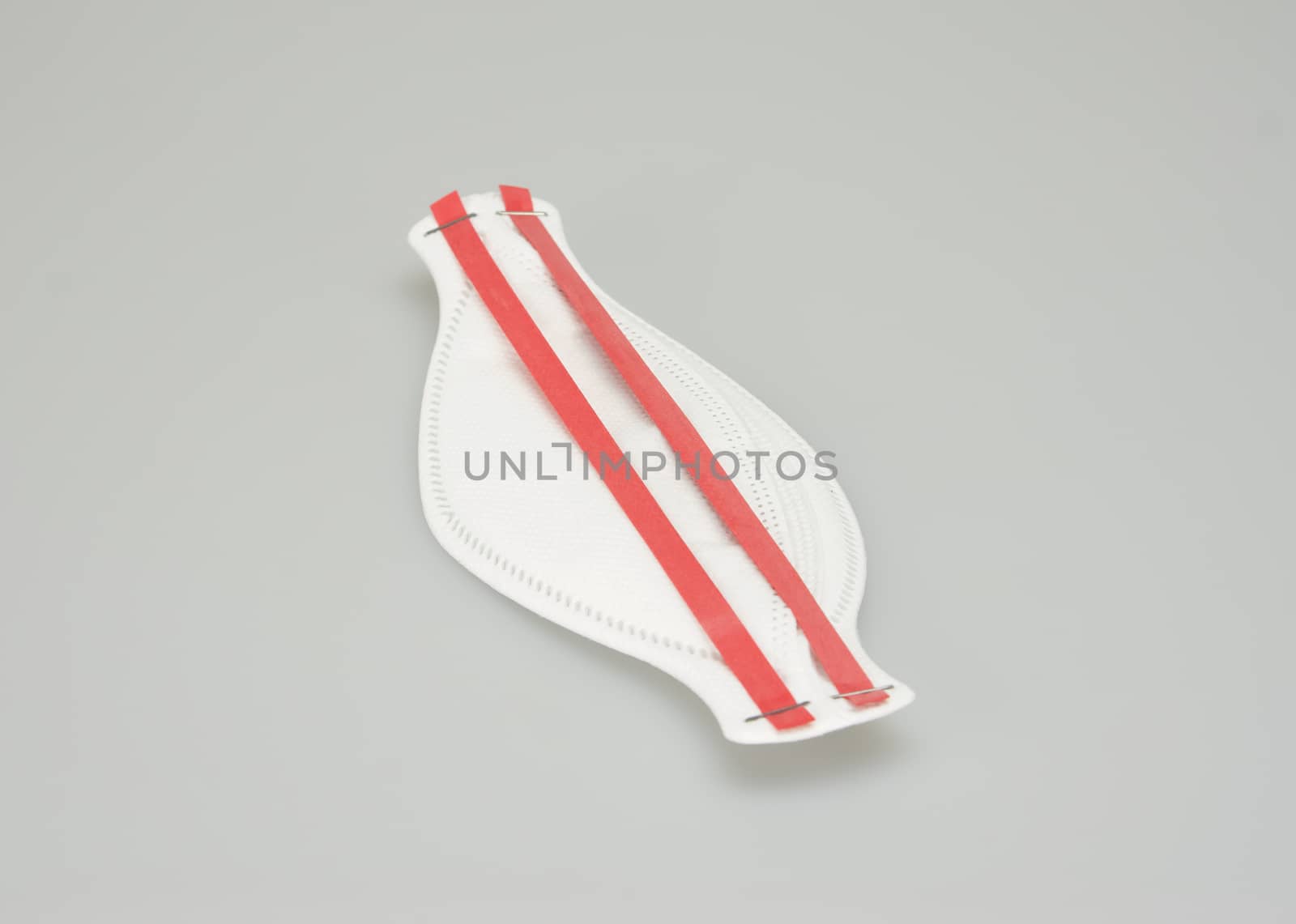 The N95 mask, oval shape, ear hook have red belt placed on white background.