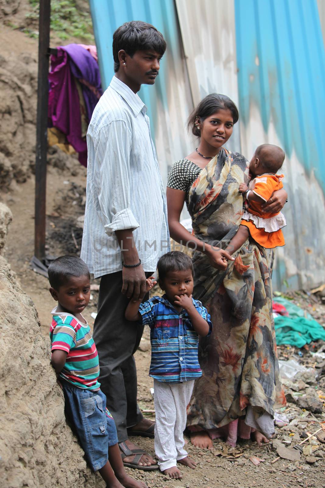 A poor Indian family of father mother and three children standing at the construction site they work at.