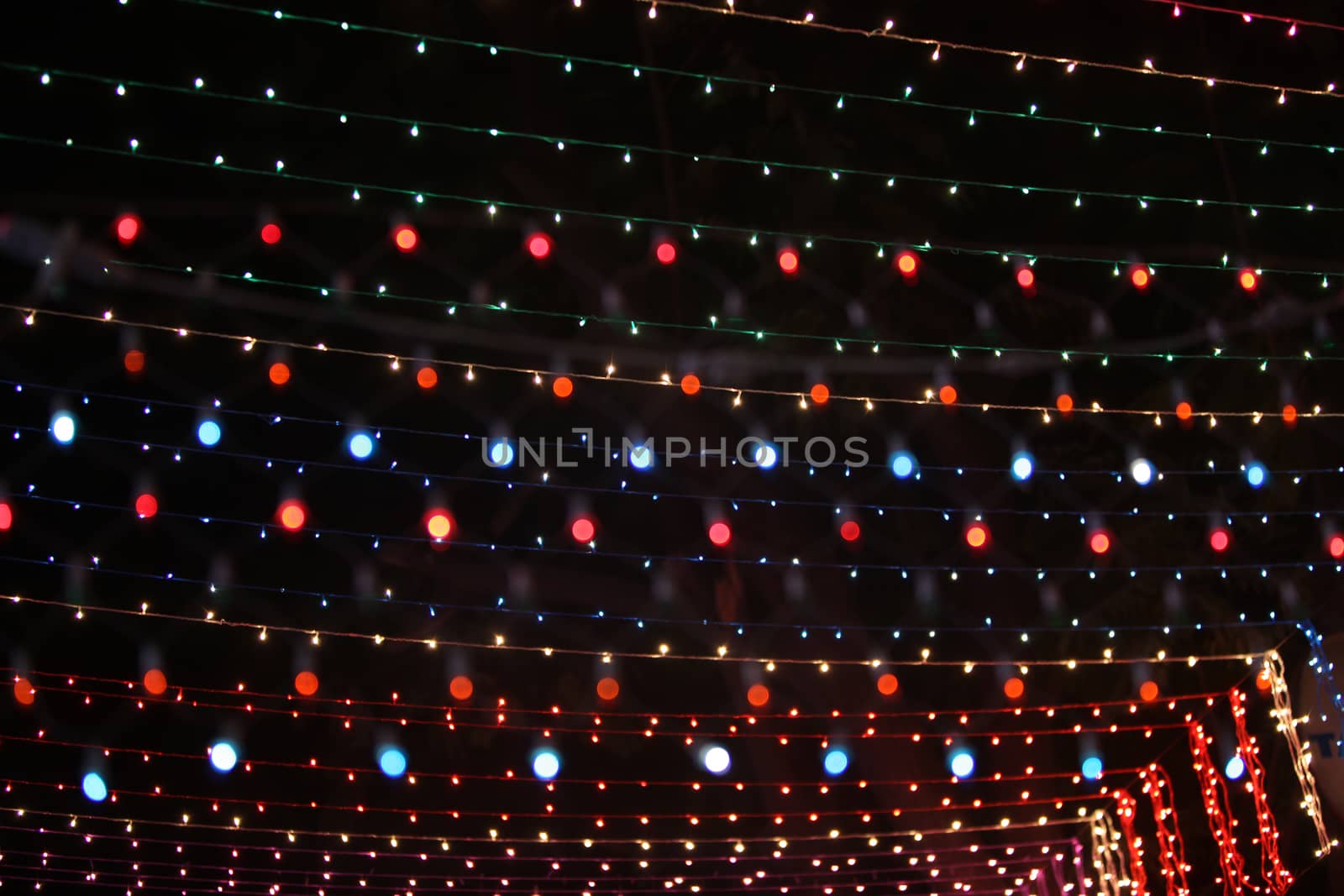 A background of colorful light wires setup high for decoration during a festival.