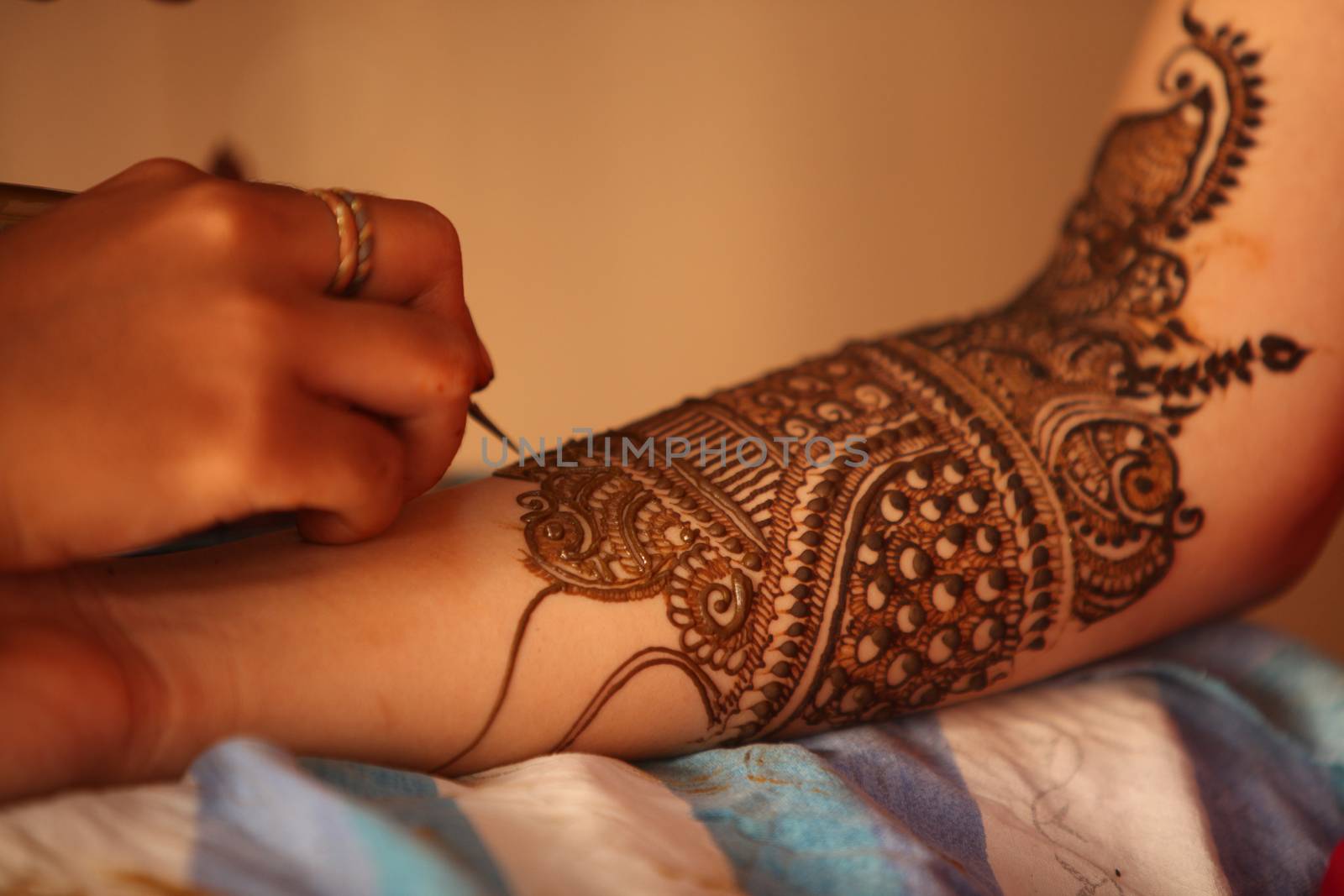 An artist making traditional design with beautiful patterns of henna or mehendi on the hands of an Indian bride.