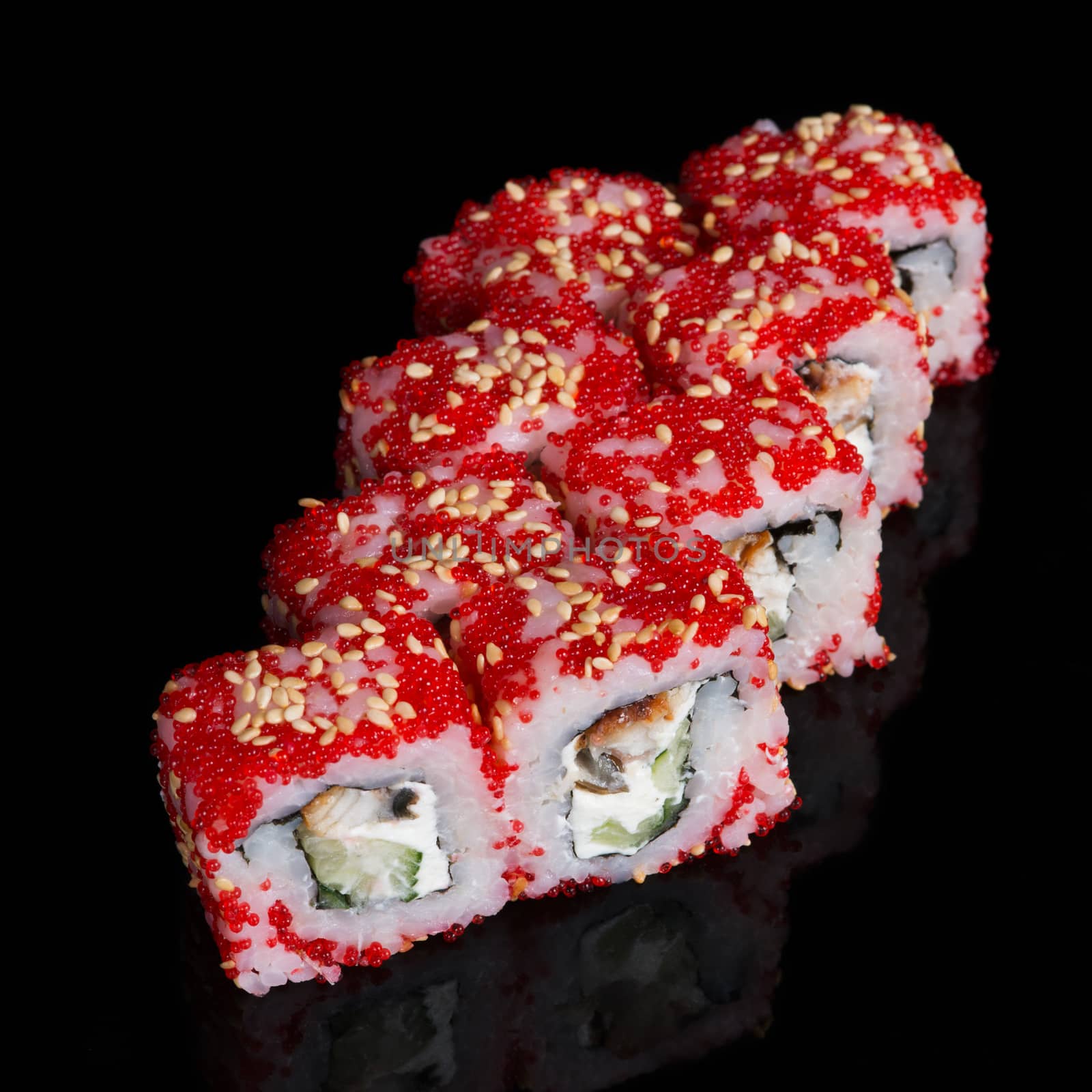Sushi rolls with soft cheese, eel, cucumber and flying fish roe on black background