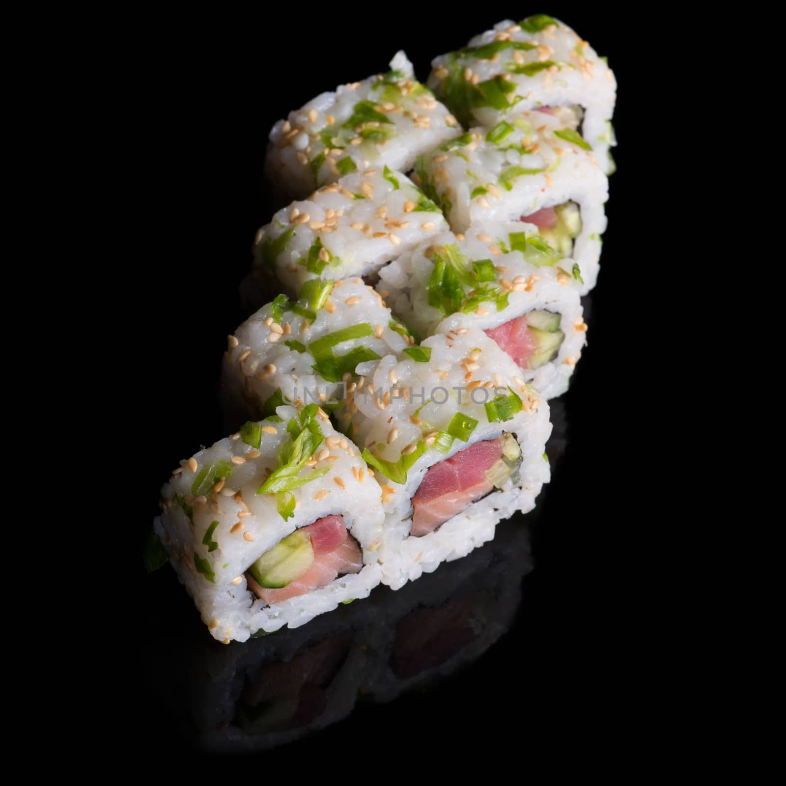 Sushi rolls with salmon, tuna, cucumber and green onions on black background