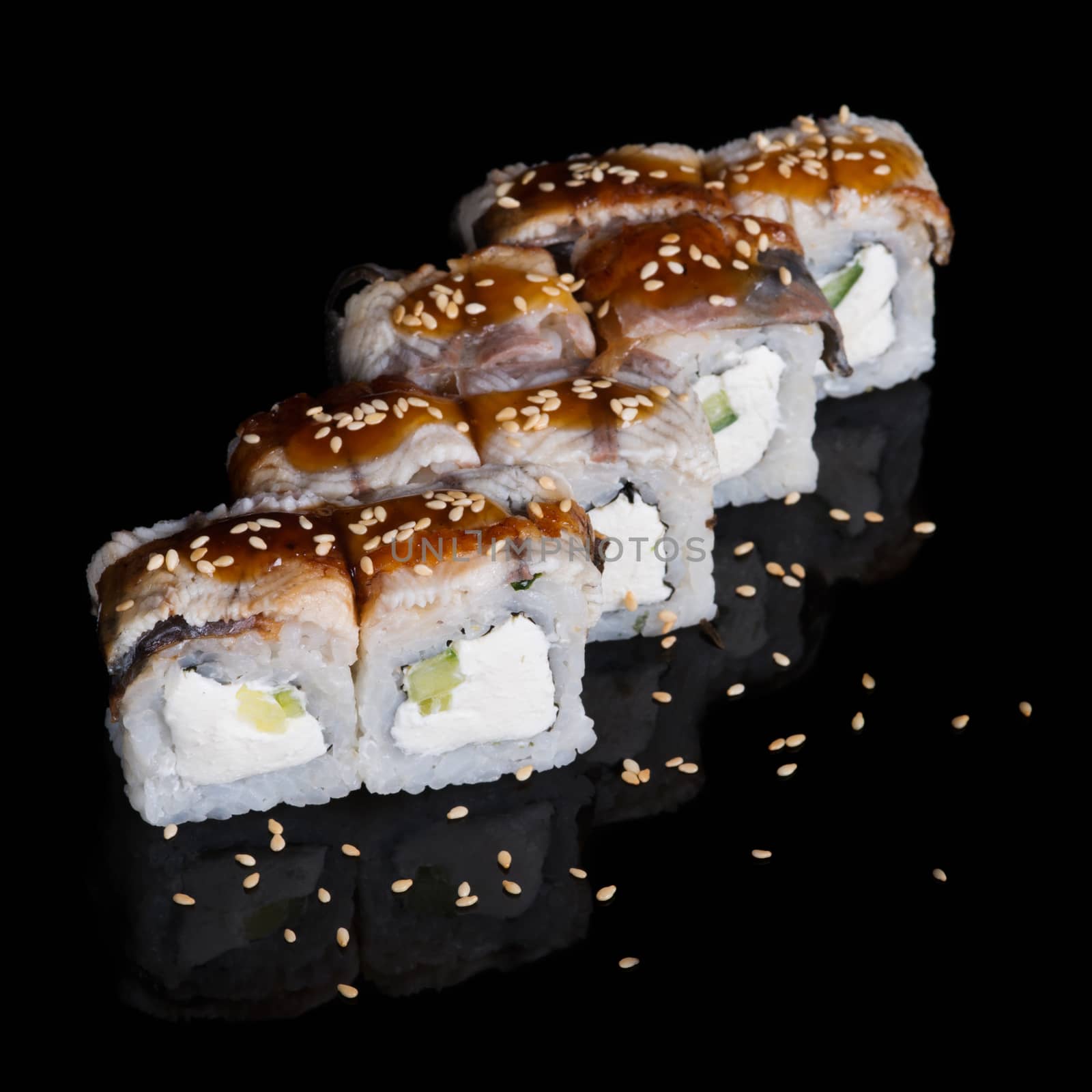 Sushi rolls with eel, cucumber and soft cheese on black background