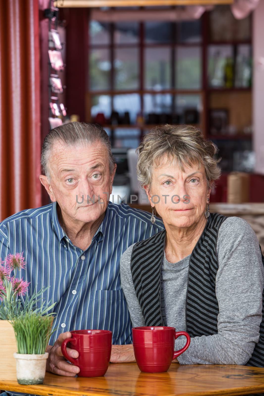 Skeptical mature couple sitting with drinks at table in a coffee house