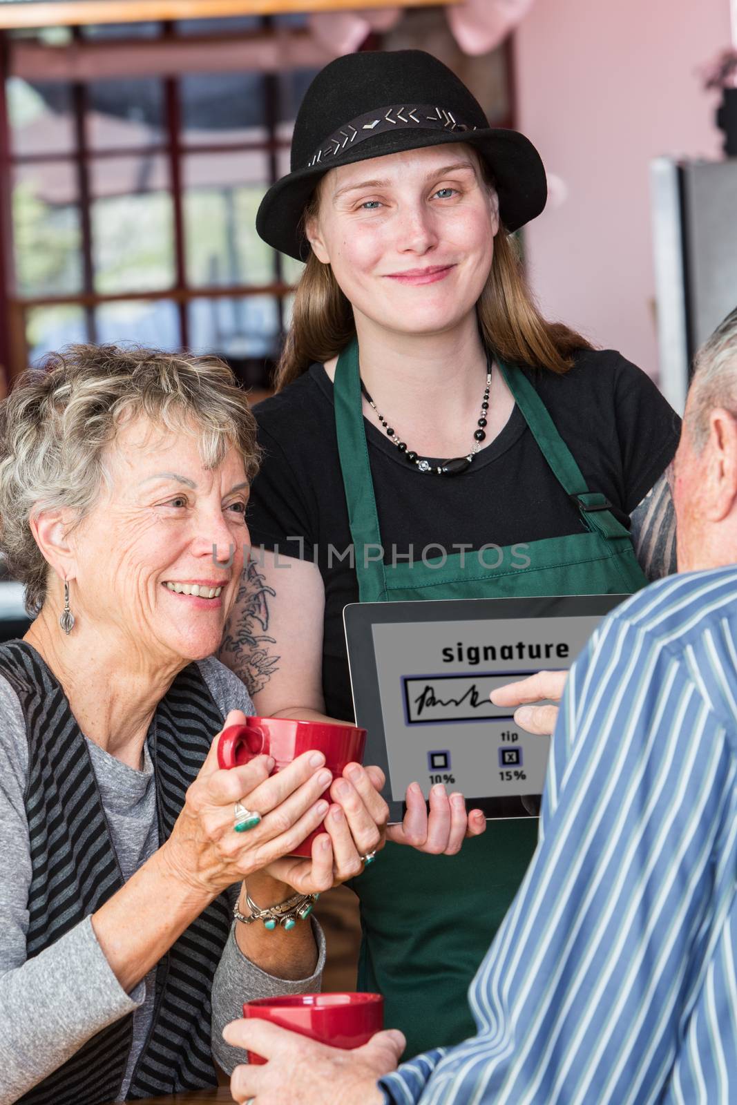 Woman watching man write signature on tablet by Creatista