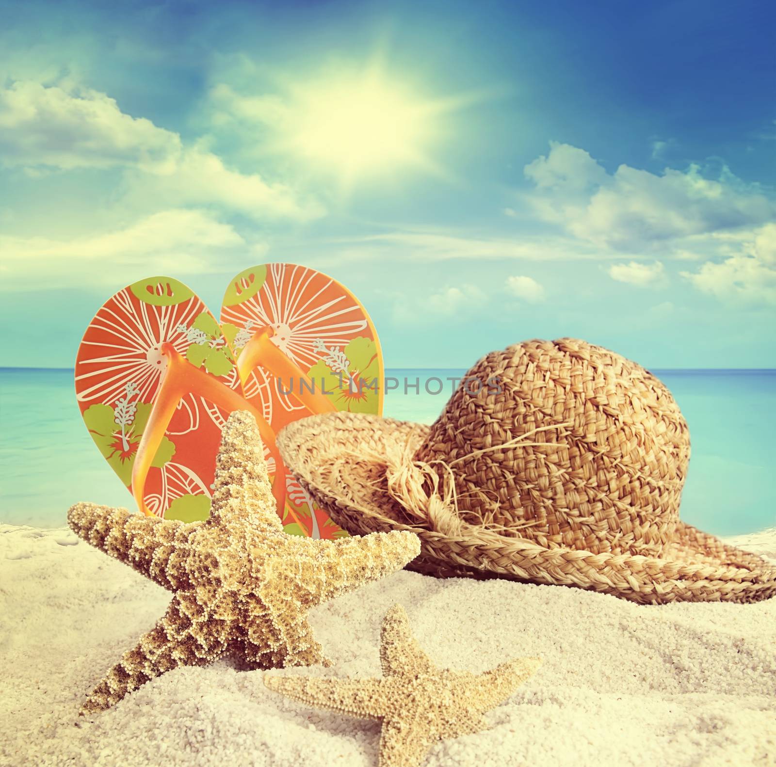 Sandy beach, straw hat and starfish in summer