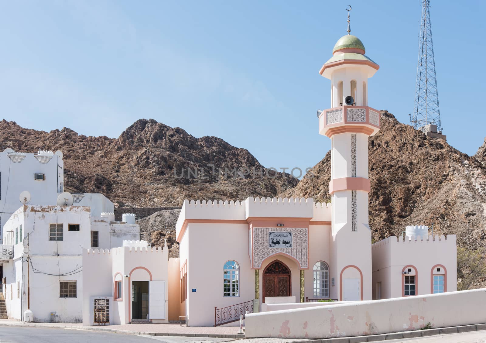 Small mosque in a typical Muscat neighbourhood with a rocky hill in the background in Muscat, Oman.