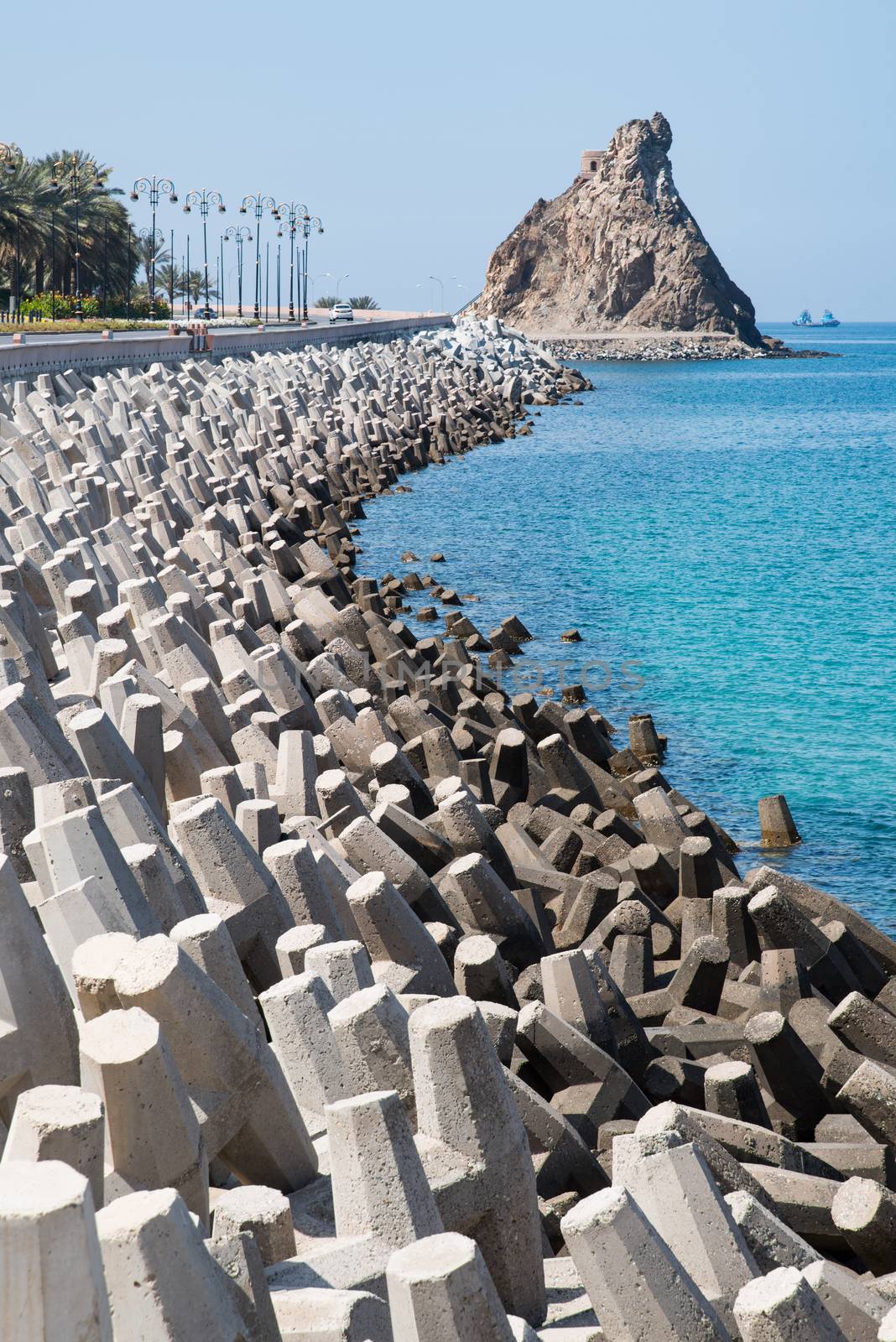 Road in Muscat, Oman, protected from erosion by concrete blocks with irregular shapes.