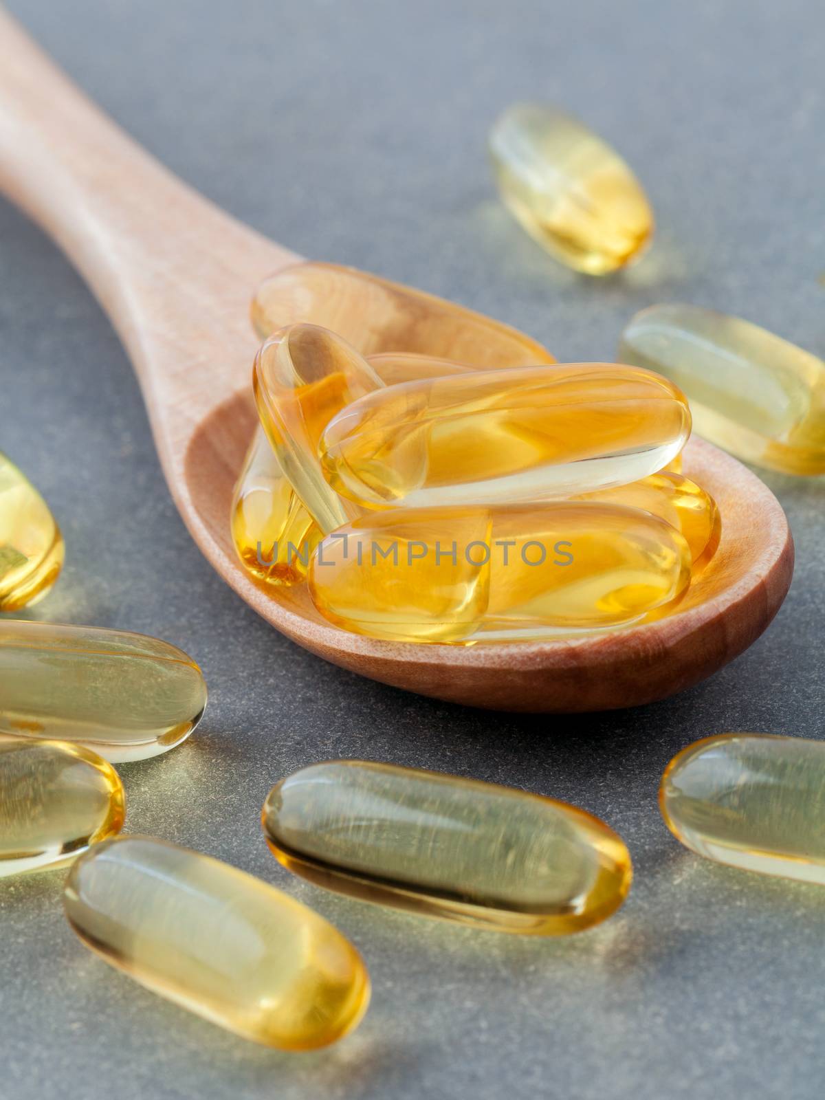 Close up capsules fish oil in wooden spoon .The supplement high  by kerdkanno