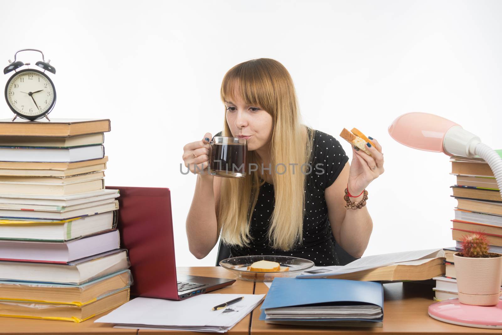 Young teacher drinks coffee with a sandwich in the workplace