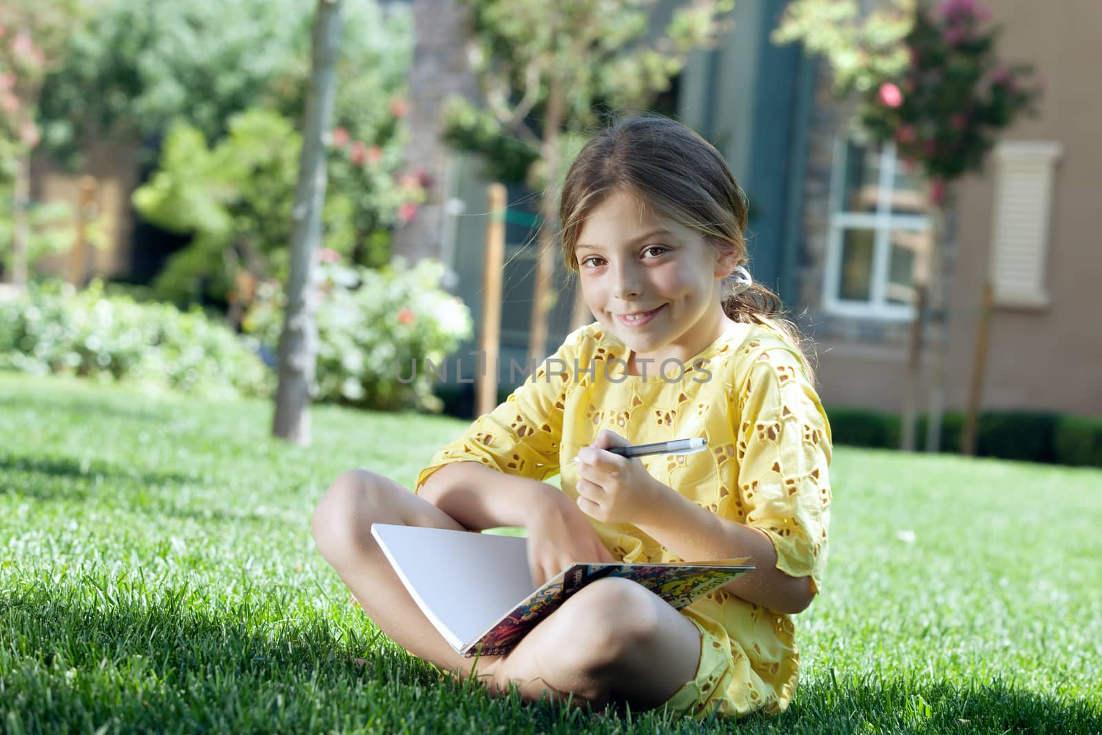 portrait of little girl studying on the grass in summer environment