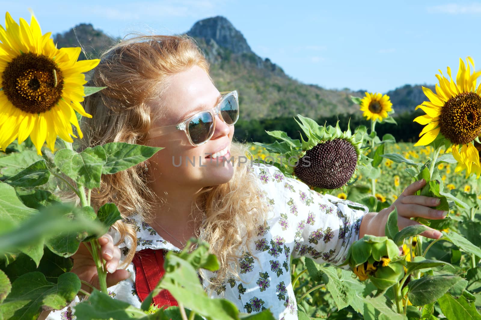 portrait of young smiling happy woman getting through the sunflower field