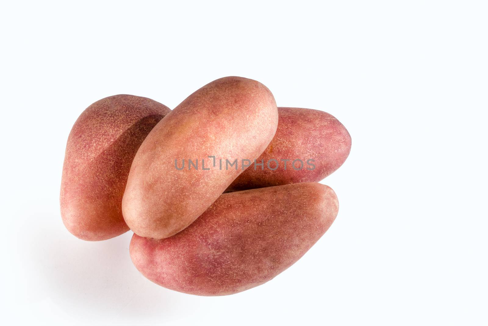 Four large red potatoes are heaped against a white background