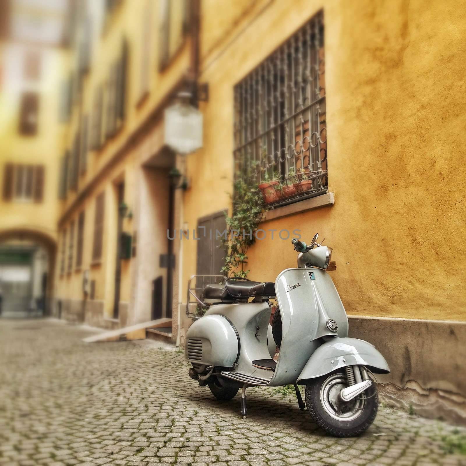 a 60's vespa motorcycle in a typical italian old town alley.