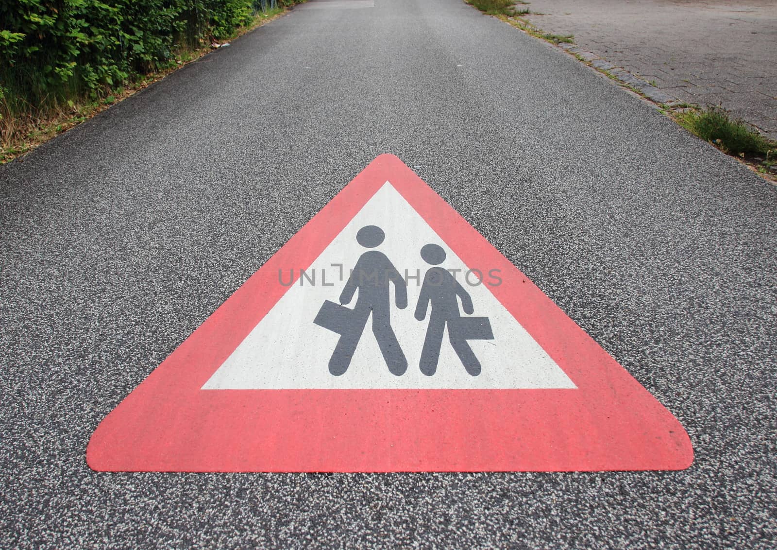 Sign on asphalt road with school or working person