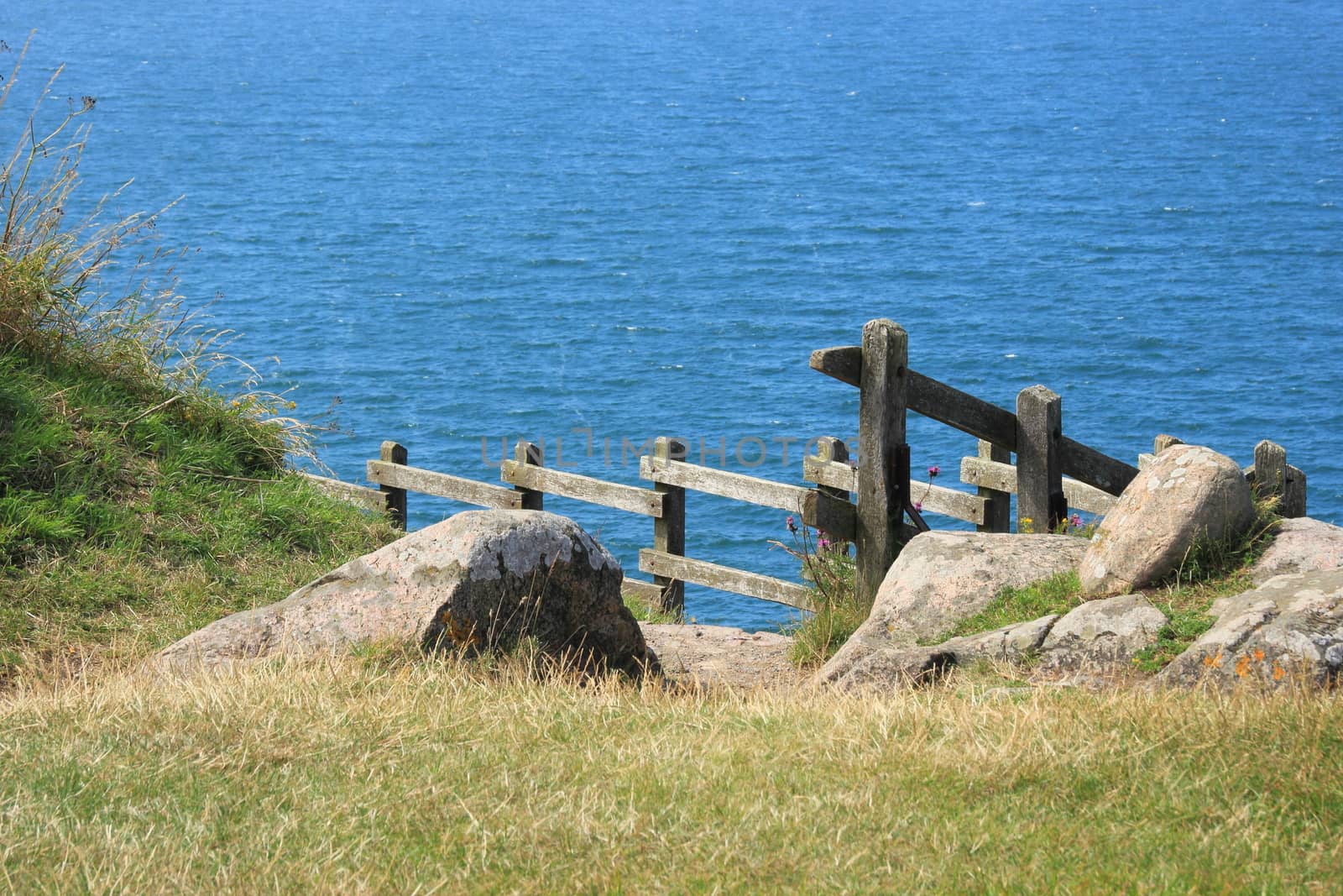 Wooden railing with path down to the blue ocean