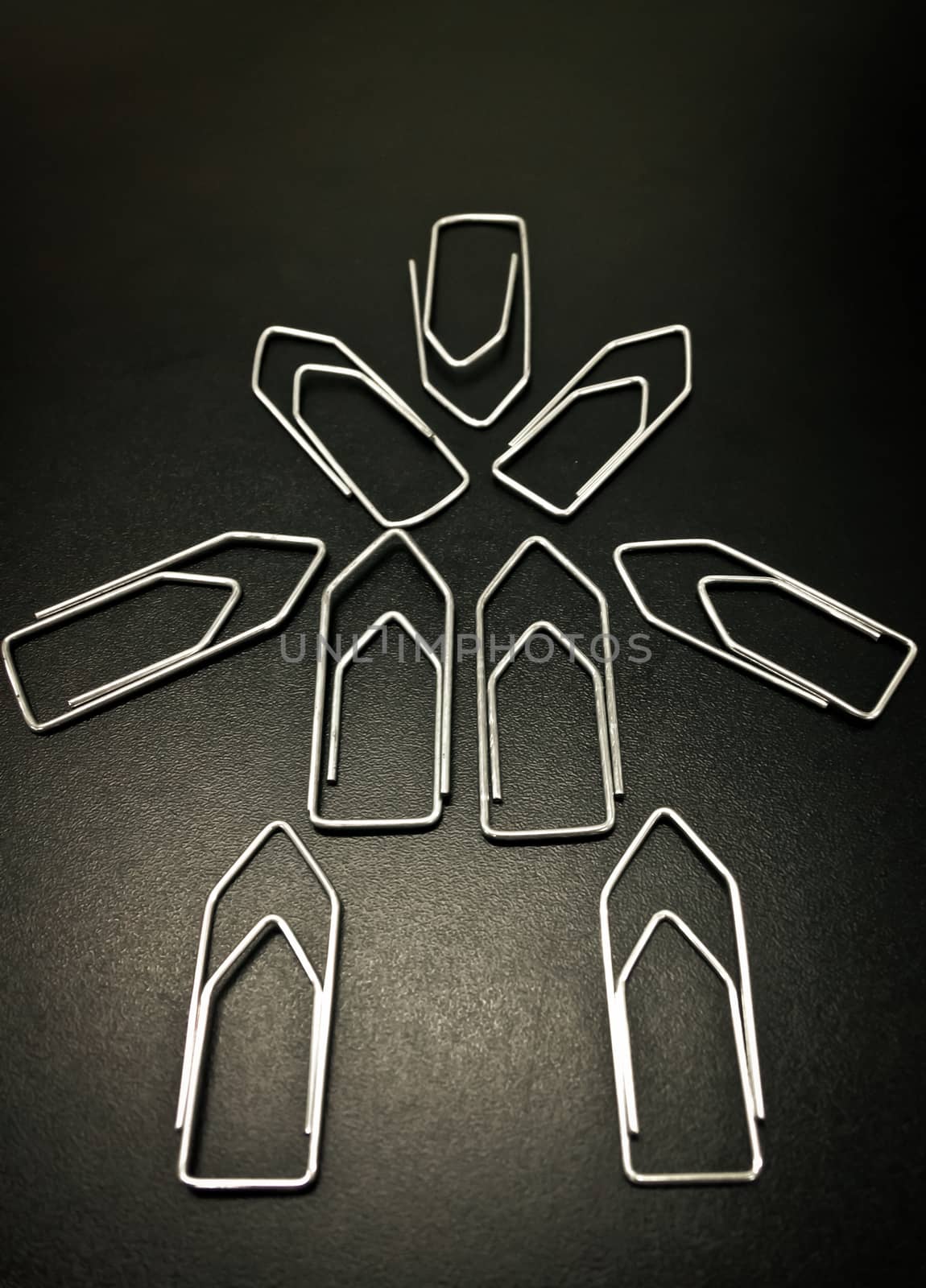 Paper clips on black desk human shape