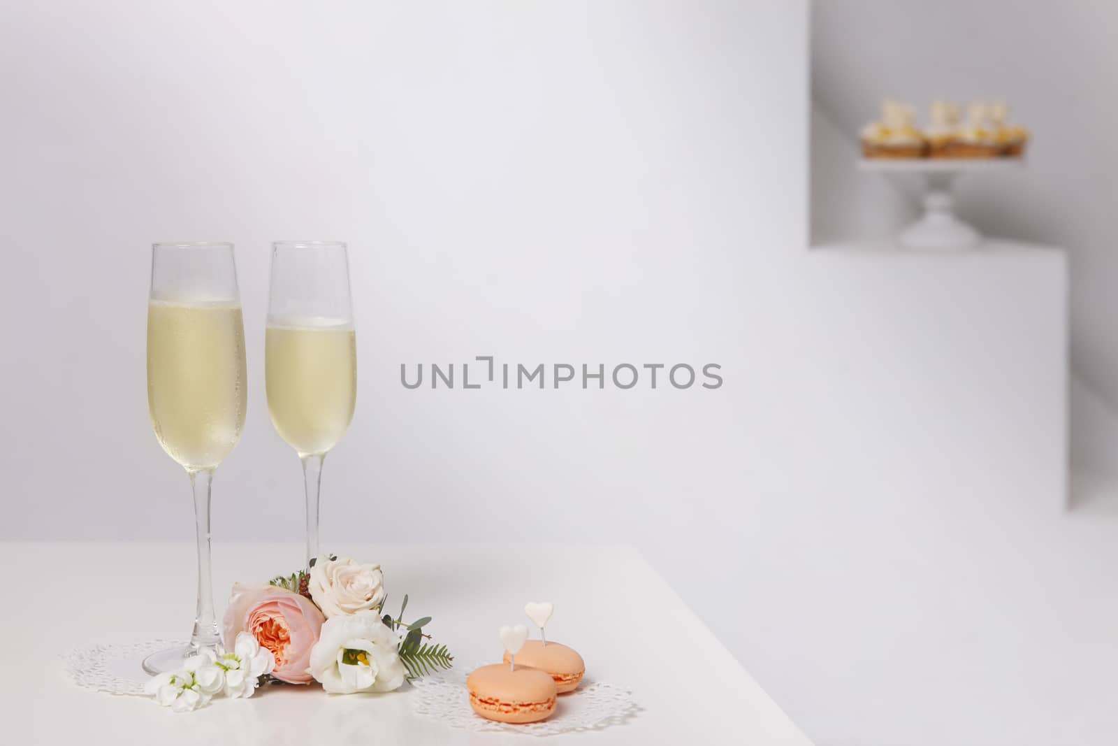 Two glasses with champagne, boutonniere with roses and cookies
