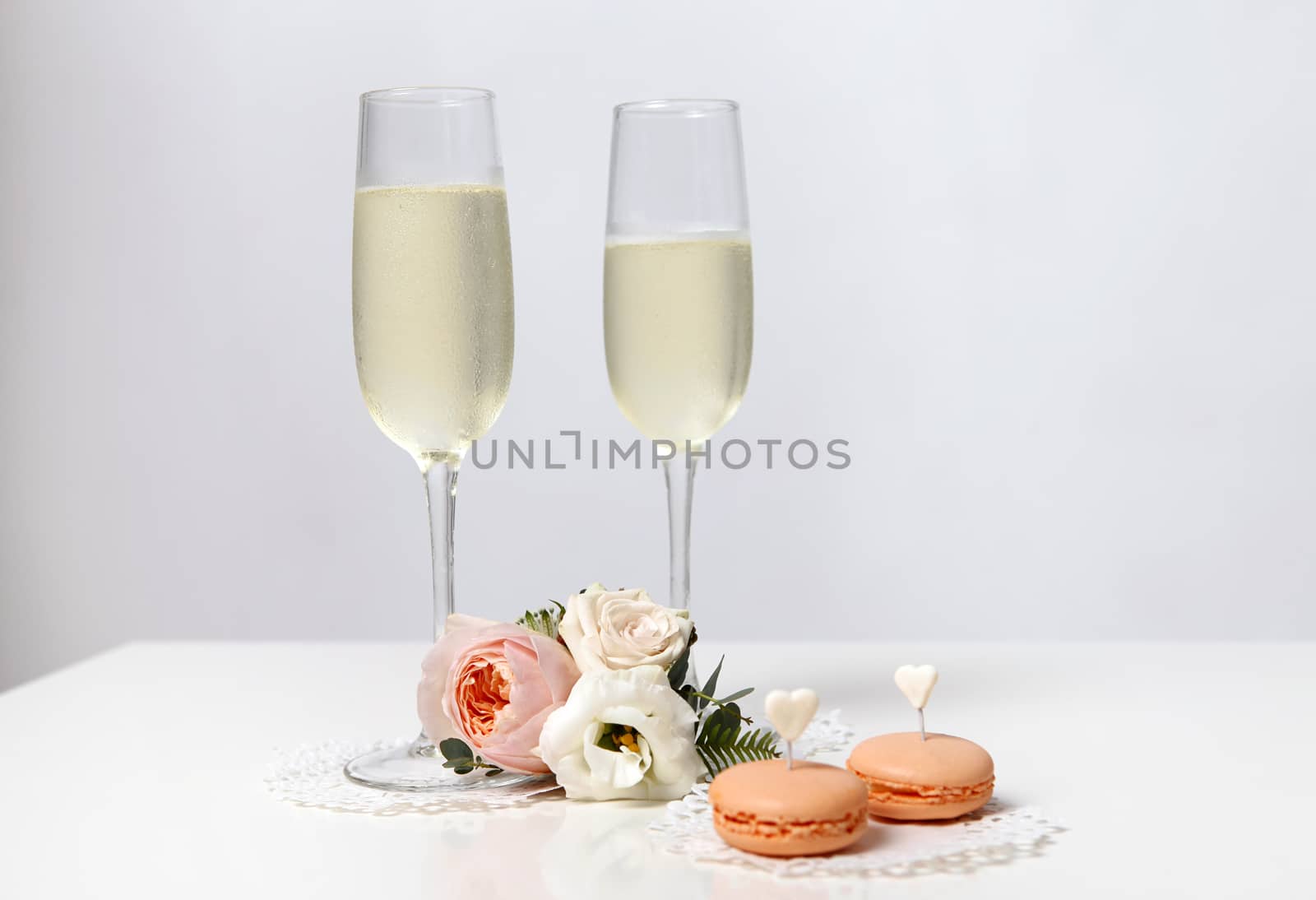 Two glasses with champagne, boutonniere with roses and cookies