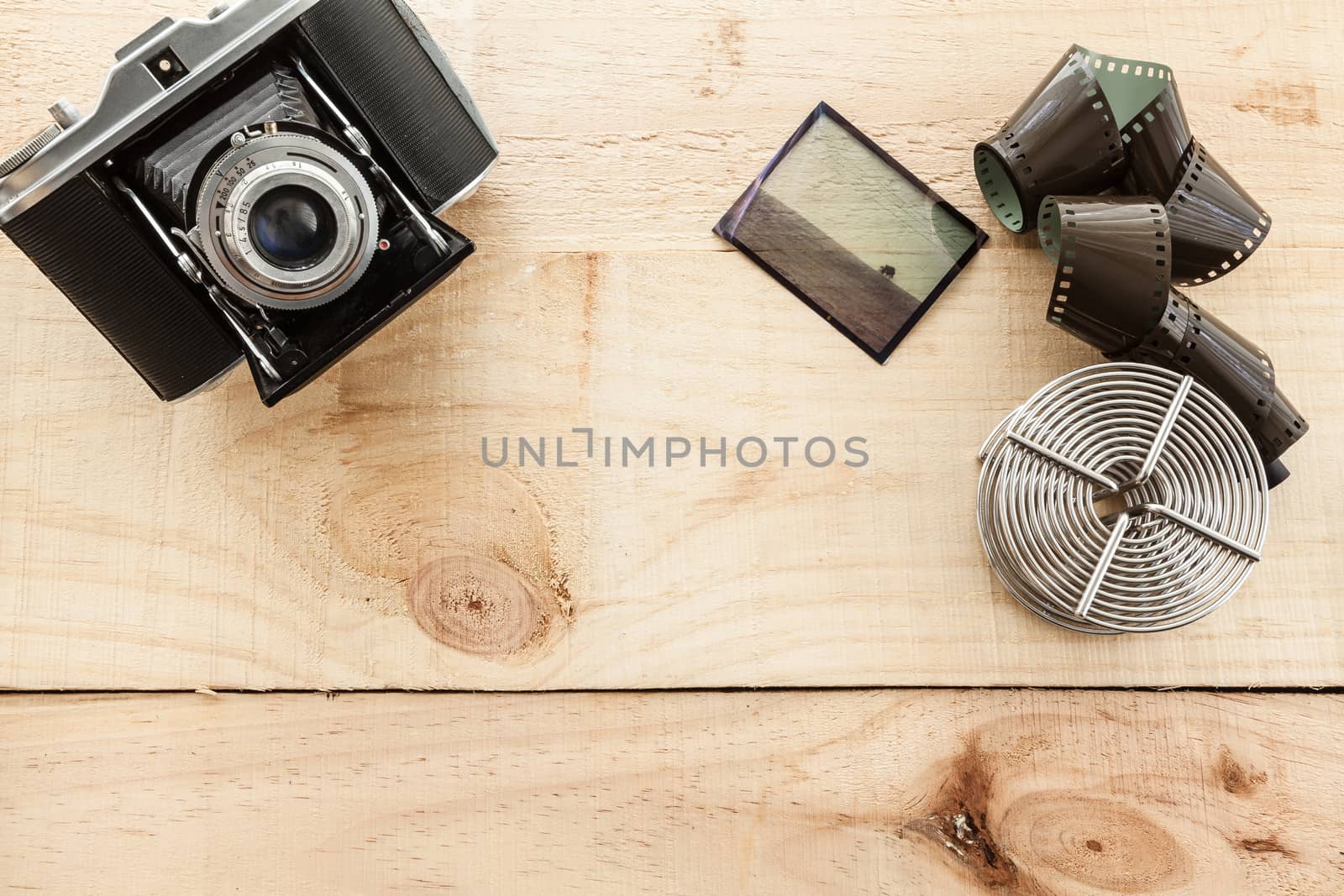 Vintage camera and color slide and film reel on a light wood table
