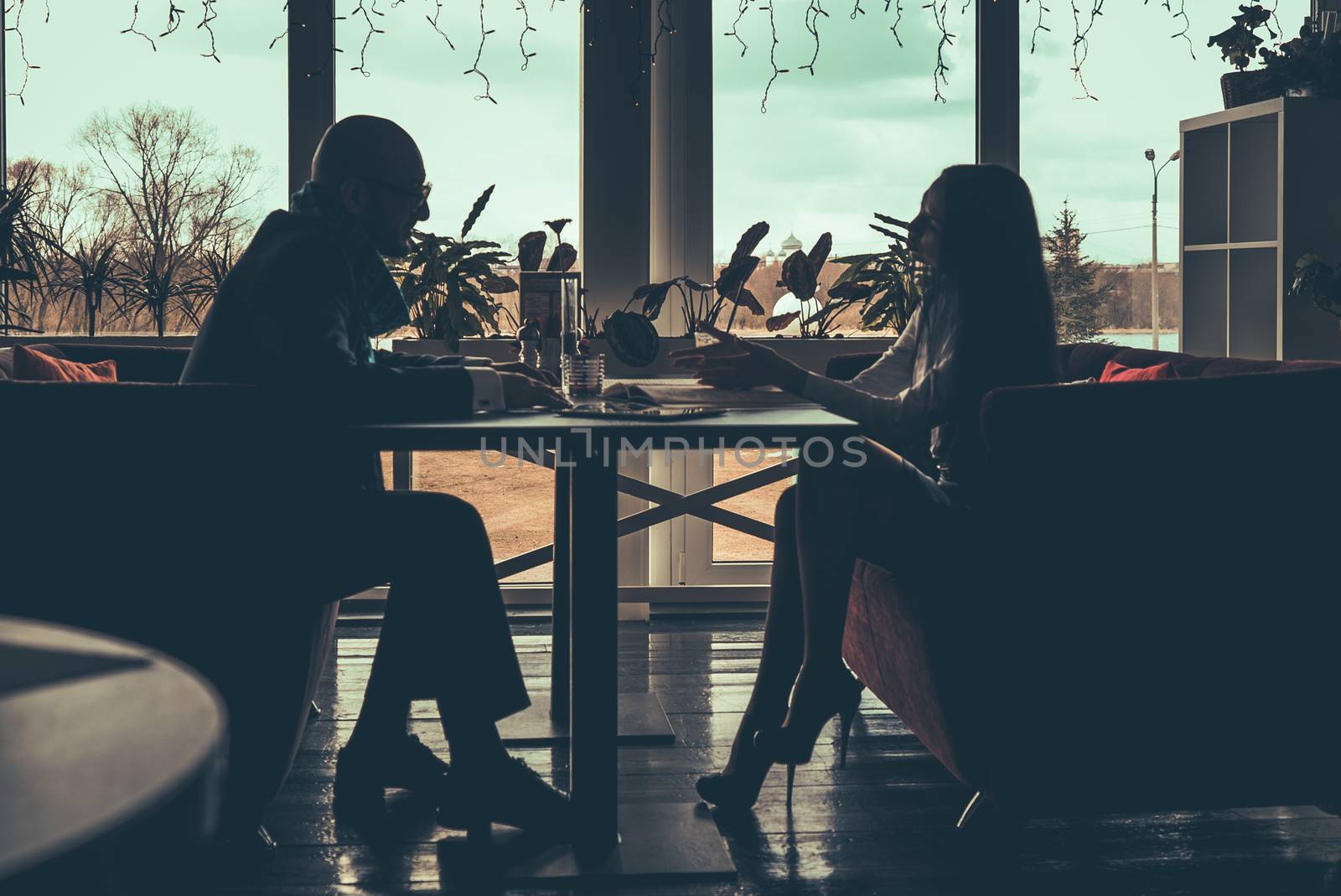 The silhouette of the love couple sitting at table in a cafe